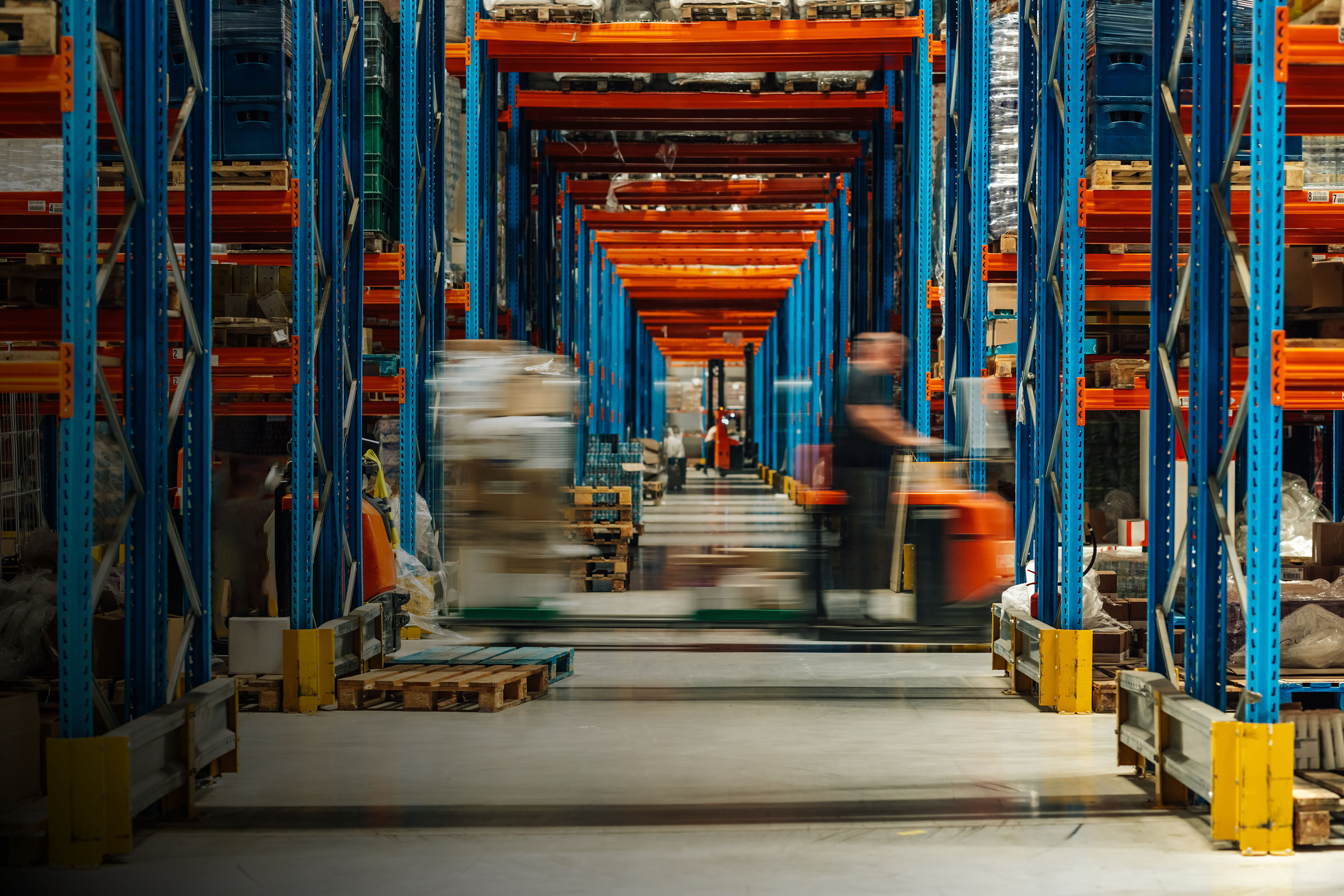 Warehouse workers operating forklifts in busy distribution center