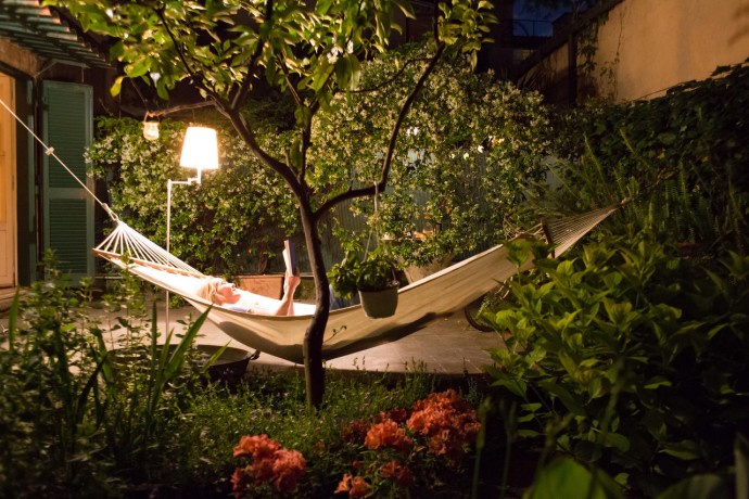 Woman relaxing in hammock in back yard at night, reading a book