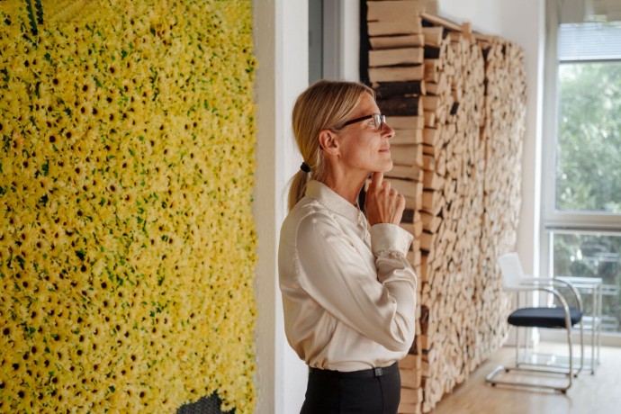 Businesswoman in office at wall with sunflowers