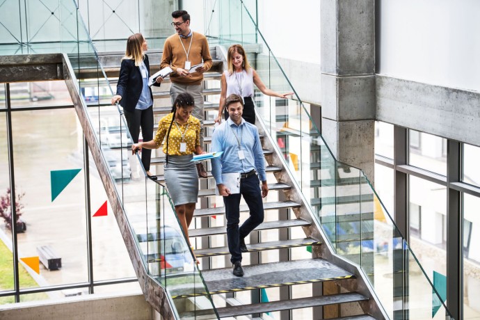 Group businesspeople walking down stairs modern building talking