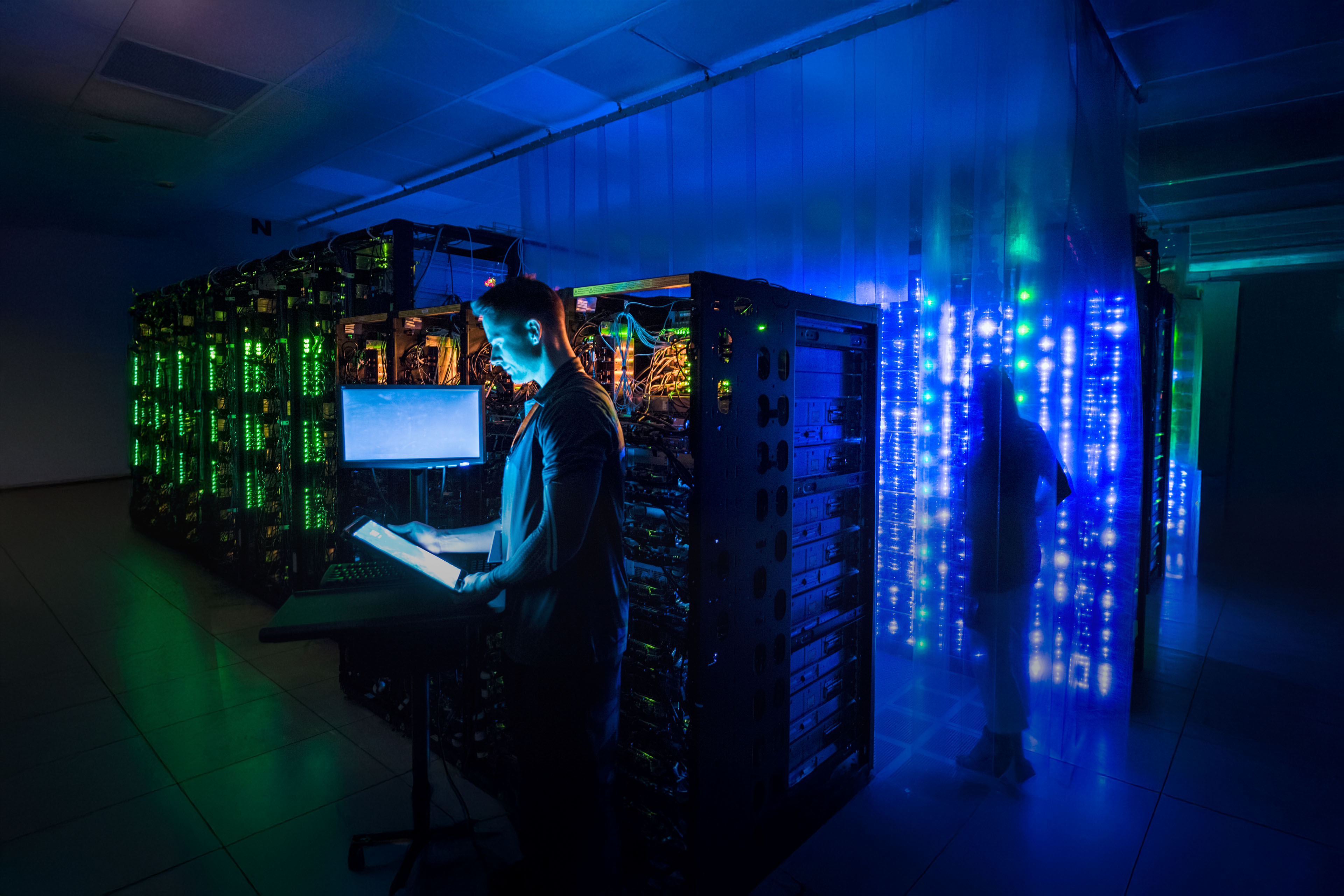 Man using digital tablet in dark server room