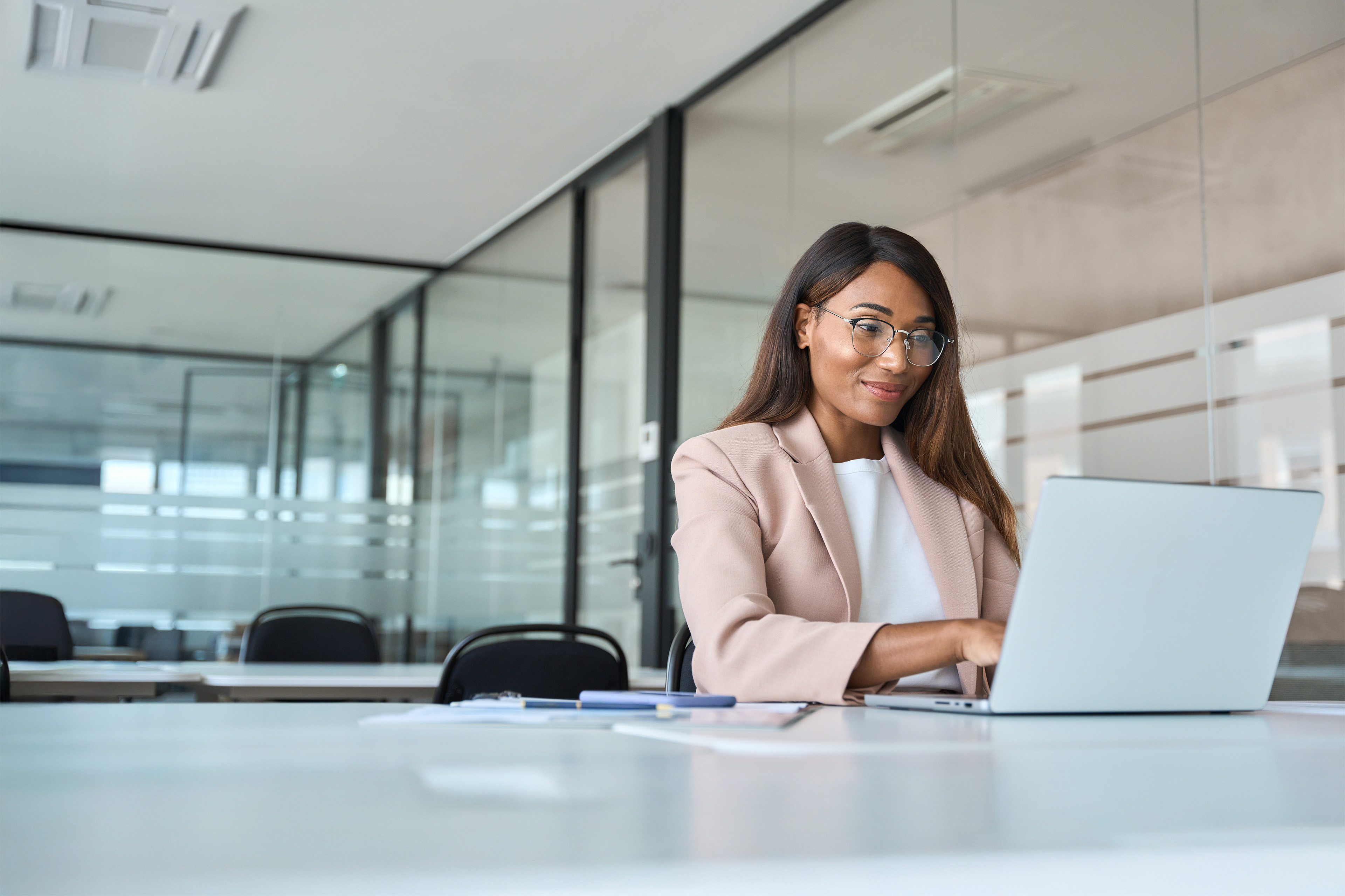 Professional business woman looking at a computer, smiling and typing in an office.