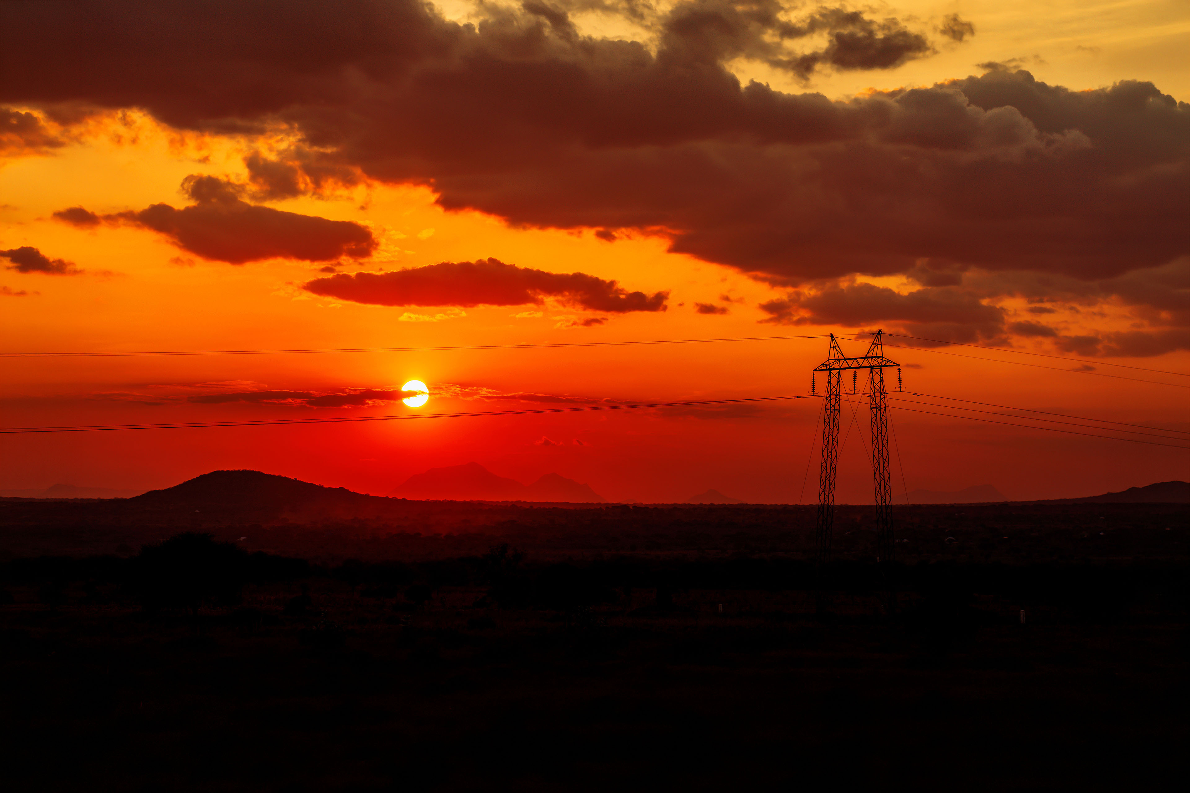 Silhouette of electricity pylon against sunset