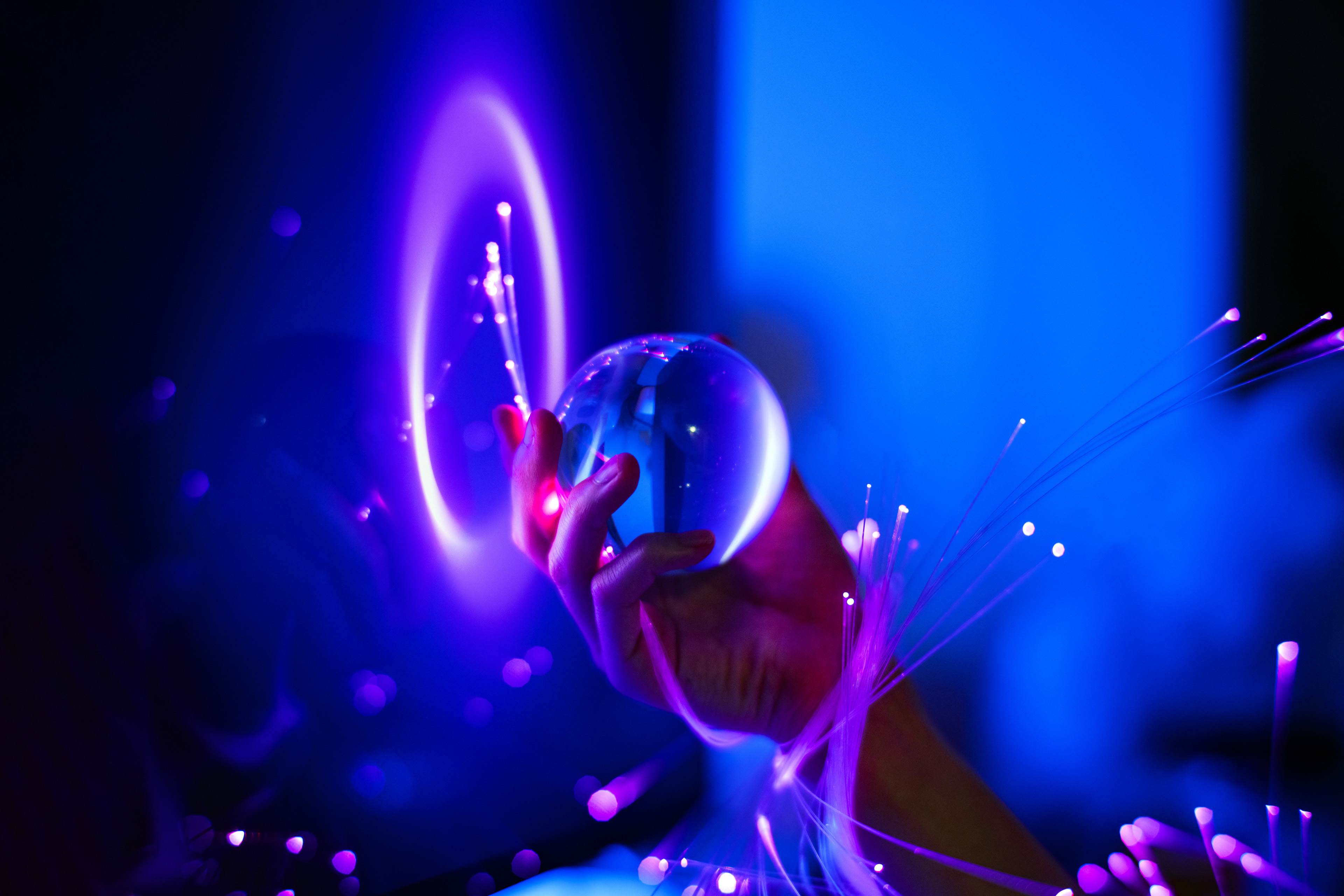 A close-up of a hand wrapped in optical fibers and holding a crystal ball