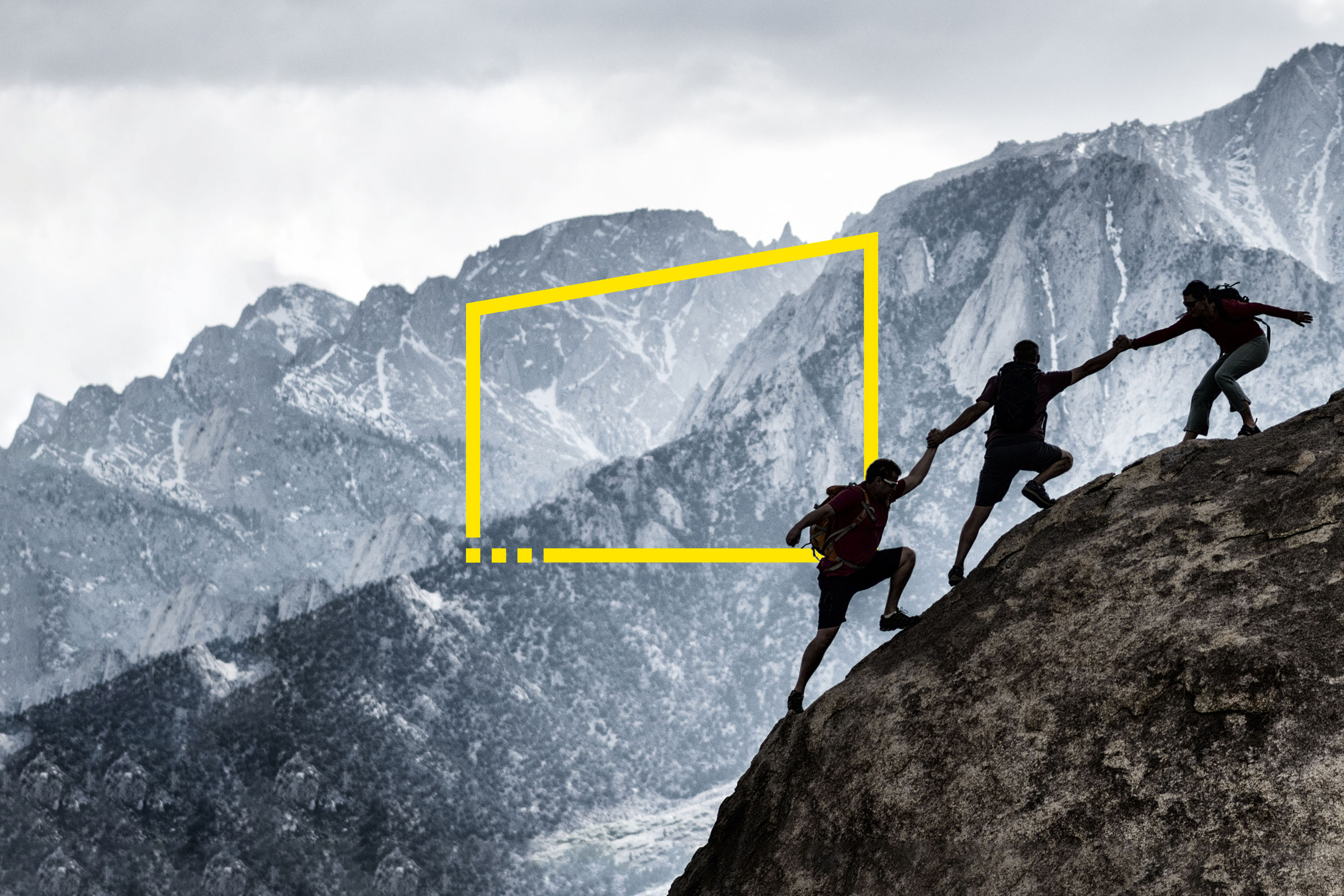 Three friends out rock climbing, helping each other in a dramatic setting