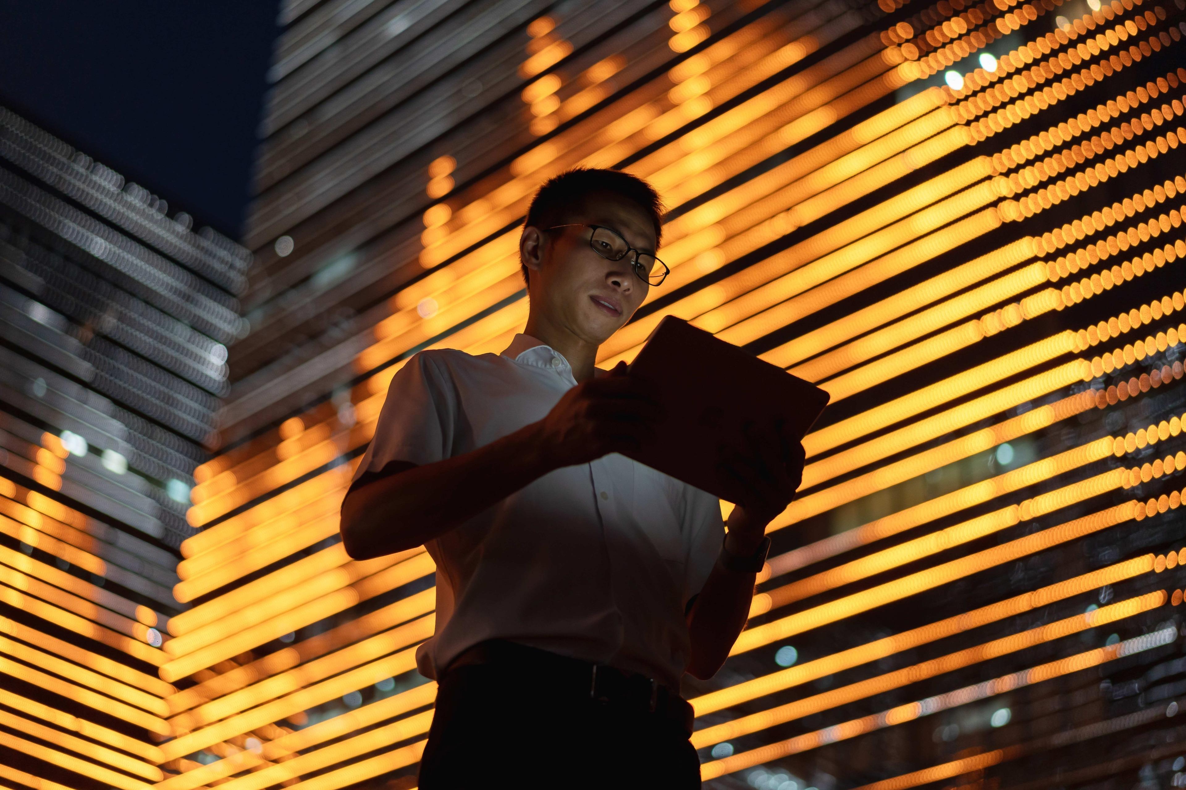 Asian worker using tablet in central business district at night