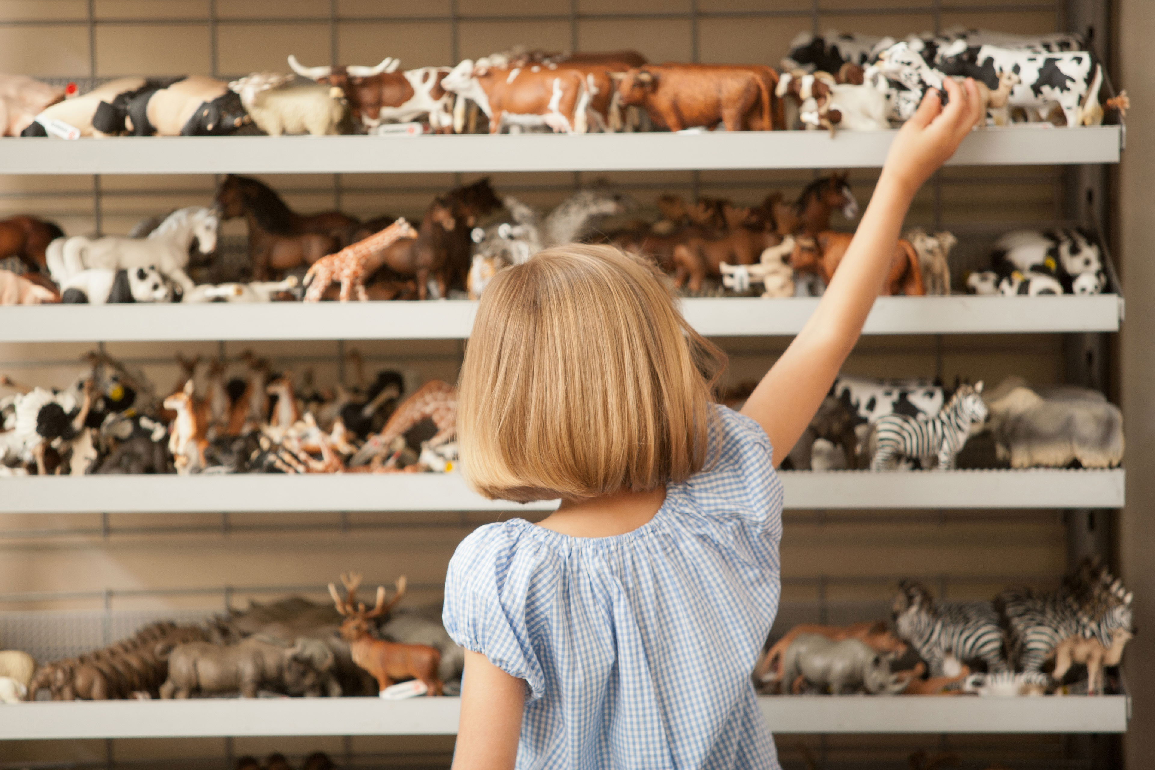 Little girl picks toy from the shelf