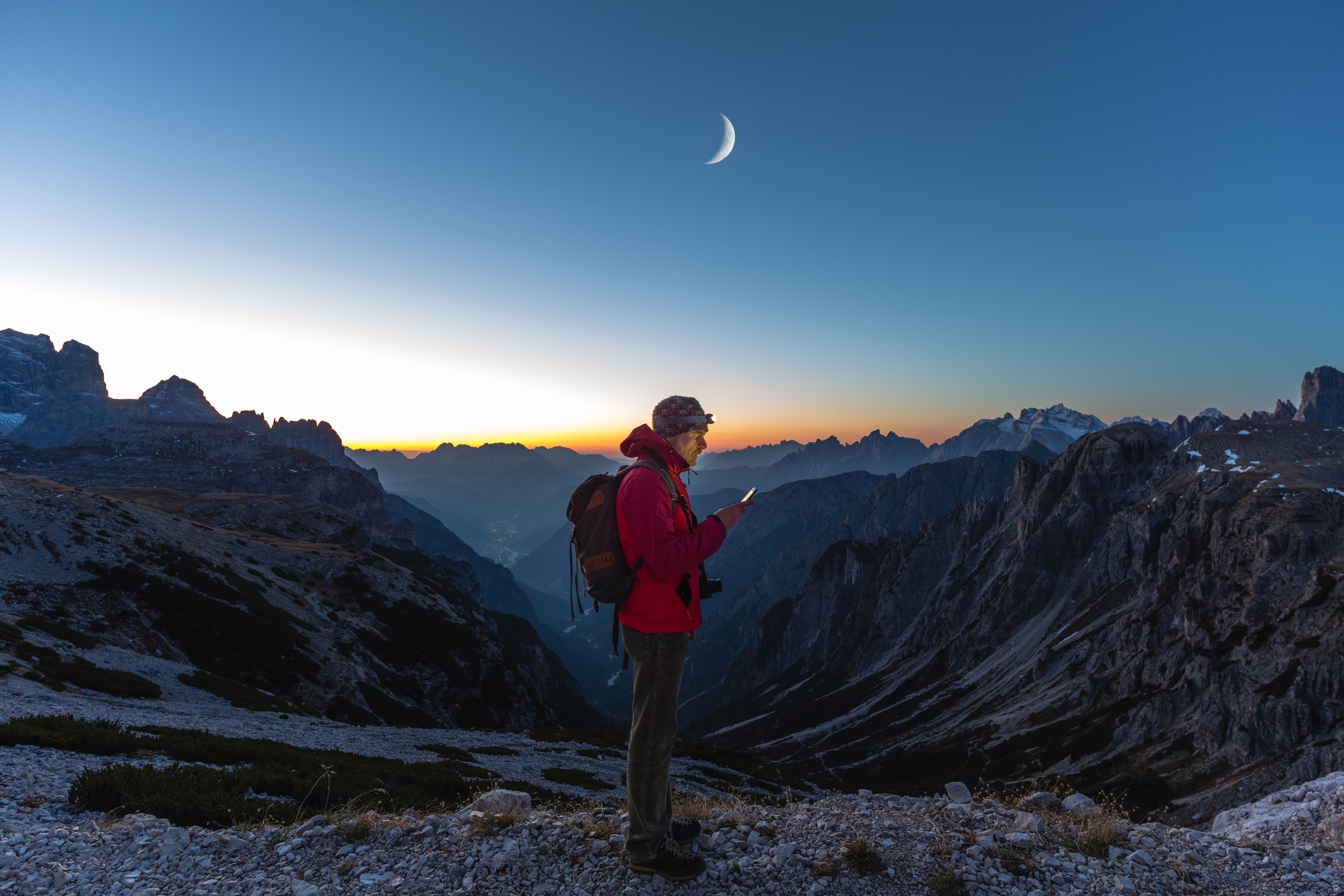 Hiker looking at map on mobile device in mountains at sunset.