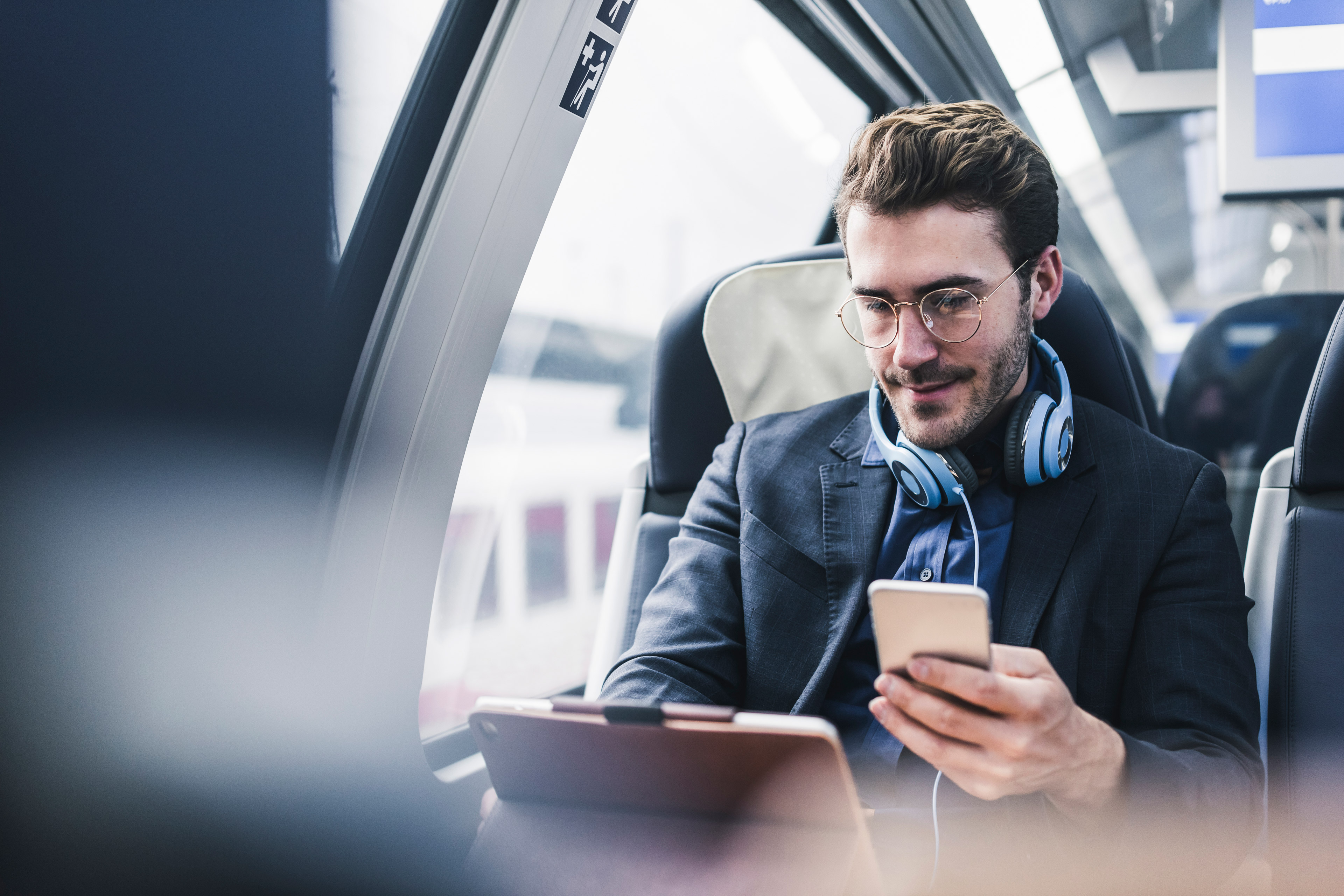 Man on train using tablet and phone