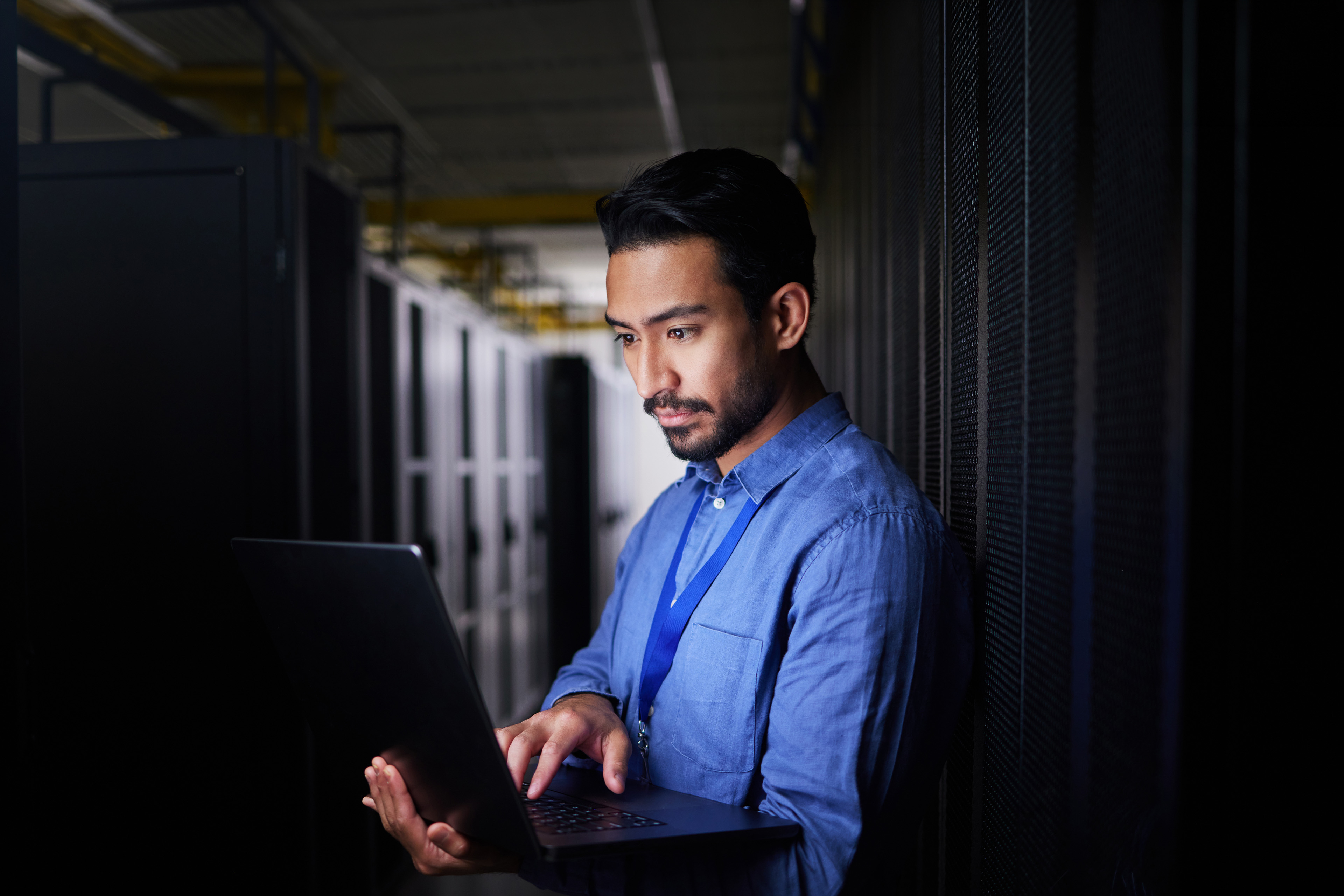 Man, server room and laptop of programming, system management and data center solution or coding at night.
