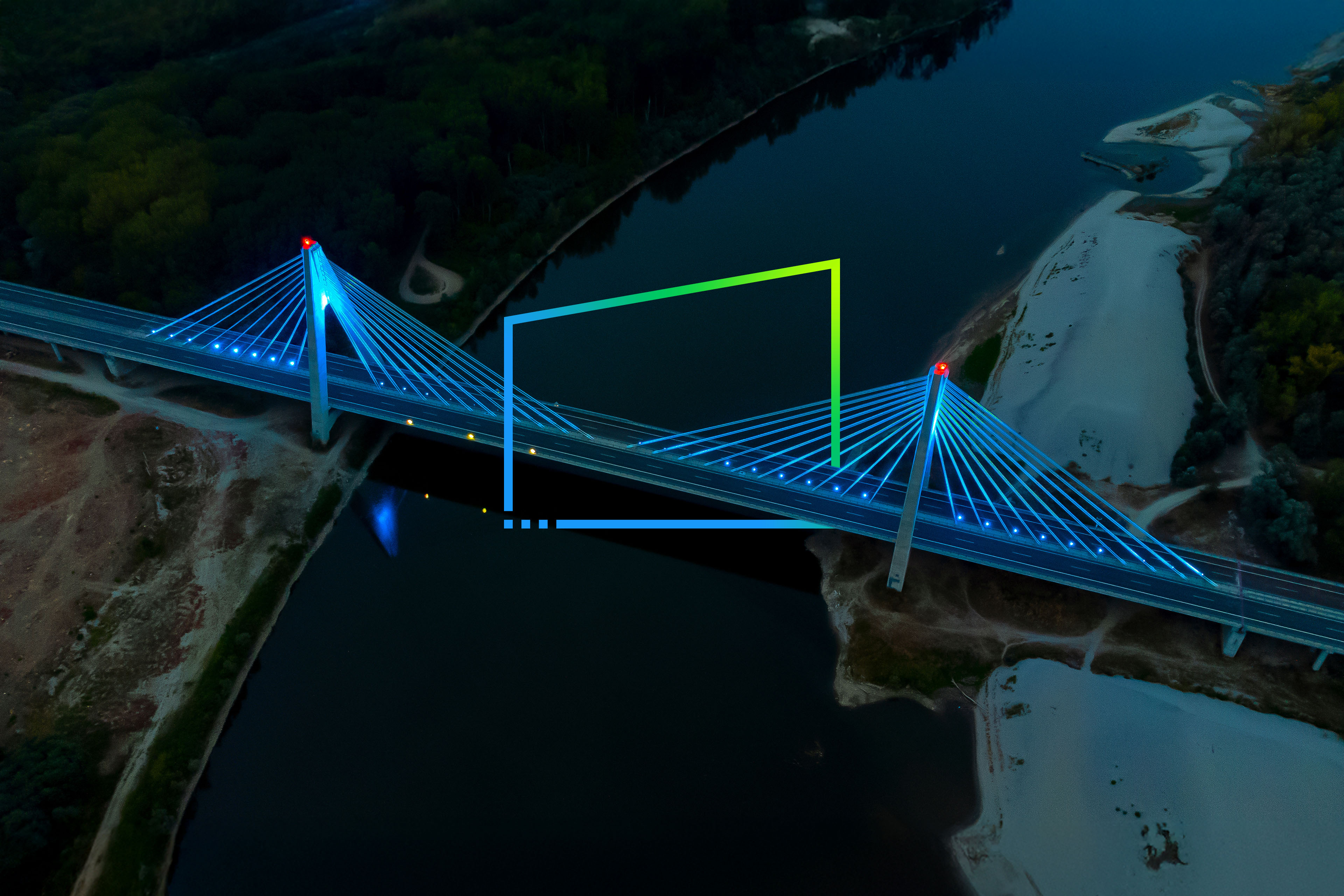 Aerial view of the illuminated cable-stayed bridge over the dark river