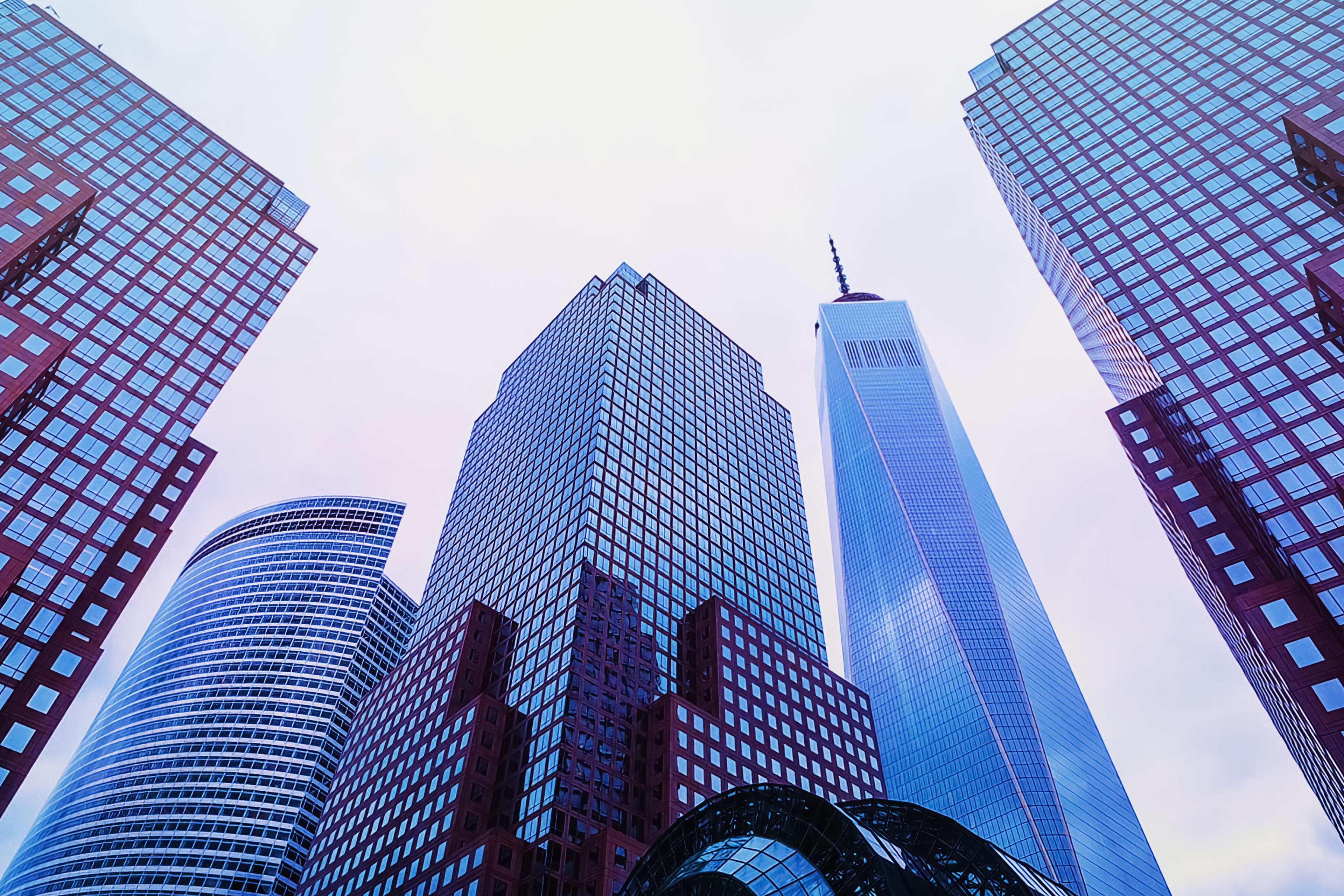 New York City skyline in Manhattan with a prominent central skyscraper, flanked by two tall buildings under cloudy skies