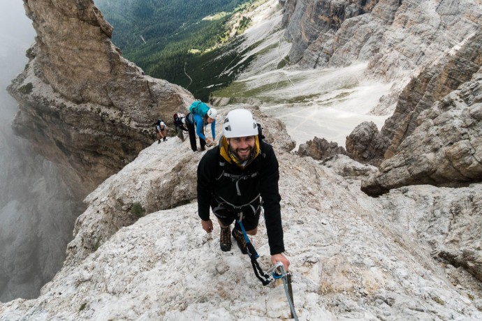 Group of young mountain climbers on a steep Via Ferrata with a grandiose