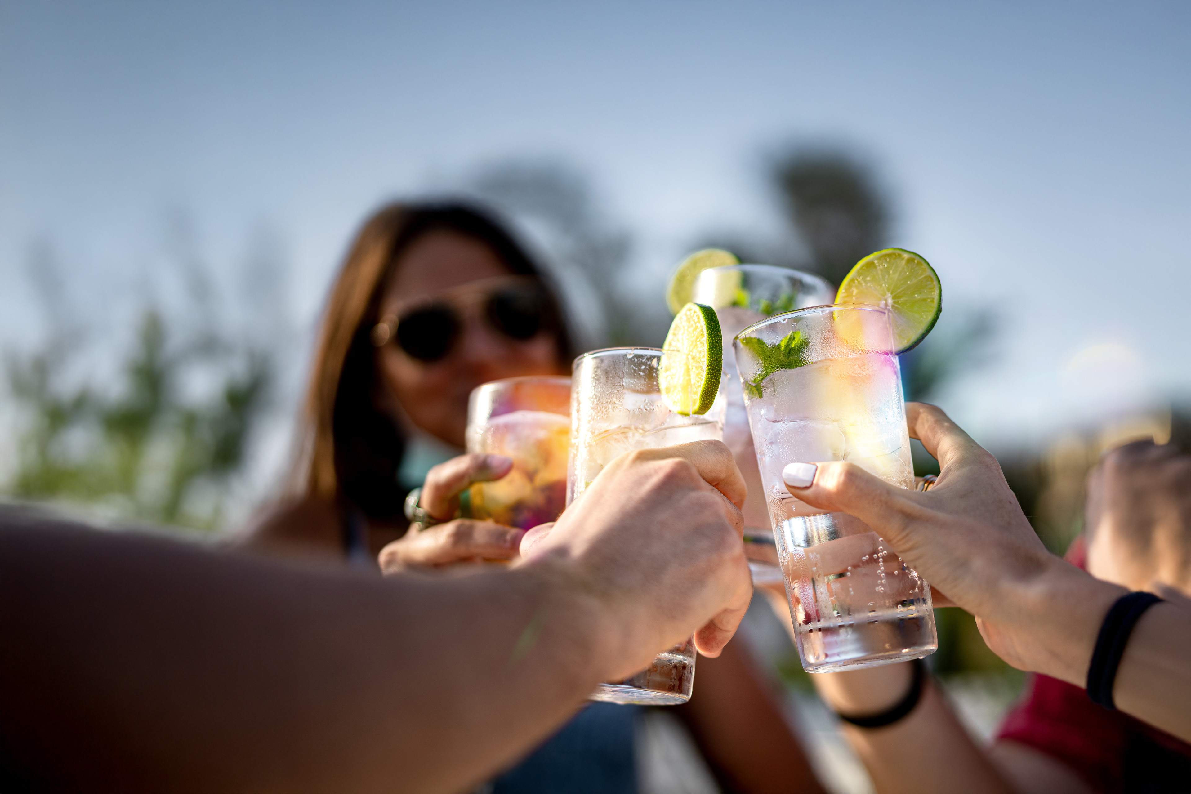 Group of young people clinking cocktail drink glasses toasting.