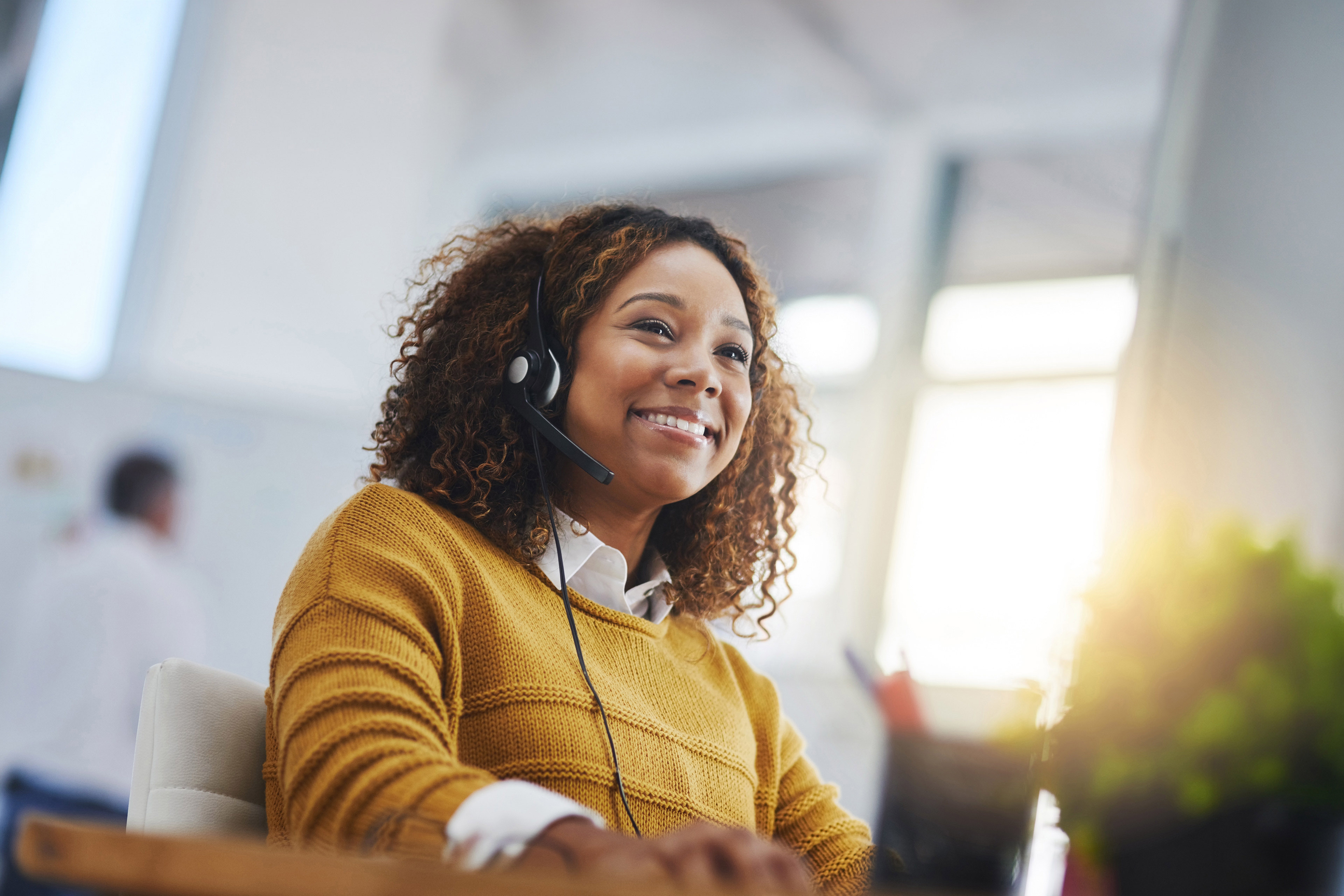 Smiling call center agent wearing headset assisting customers with support, consultation and help desk services daily.