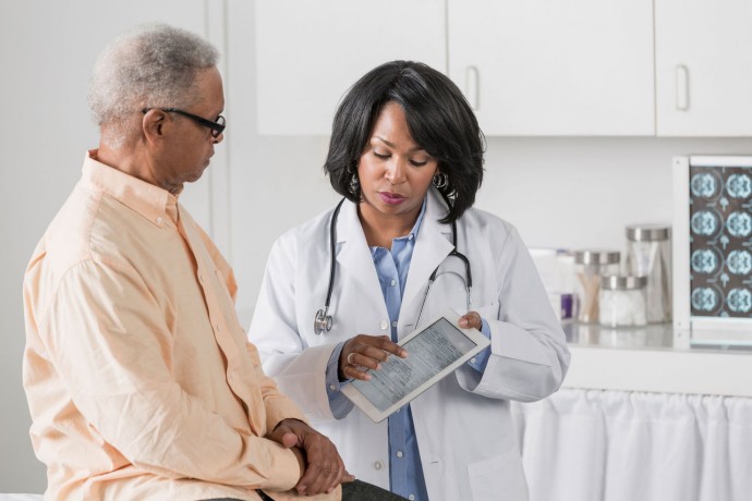 African American doctor showing patient digital tablet