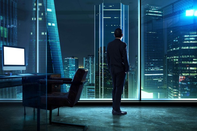 Businessman standing in office watching city night view