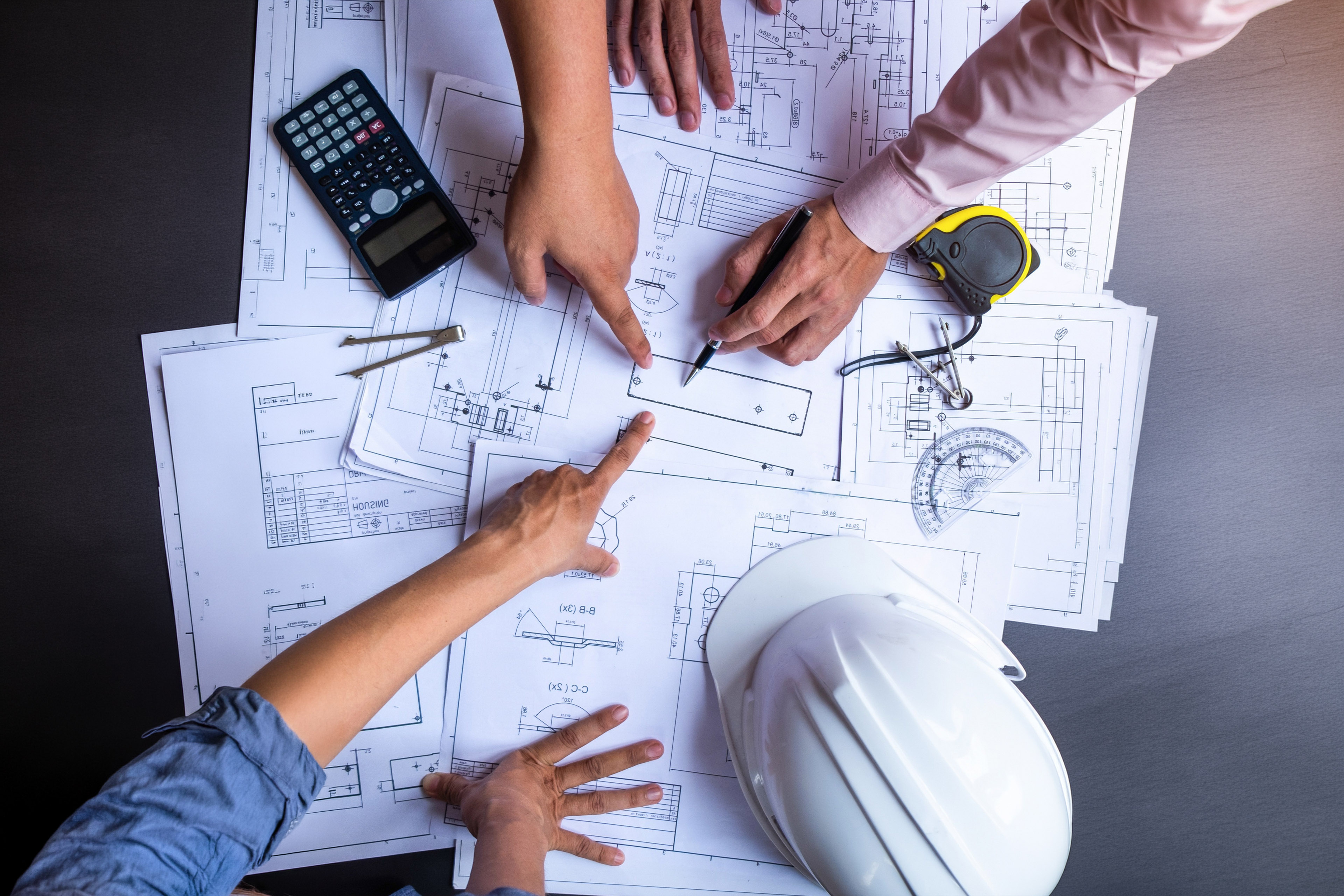 engineers pointing to building on blueprint and using pen to drawing design building Project in office