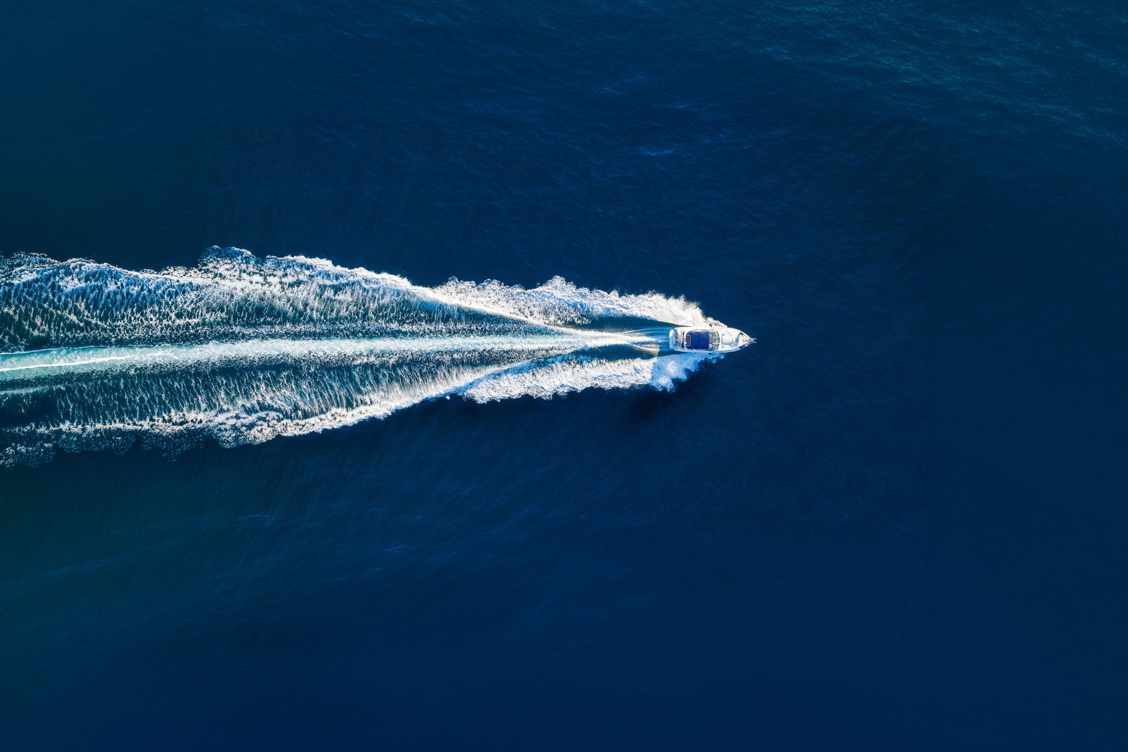 Aerial view on fast boat on blue Mediterranean sea at sunny day. Fast ship on the sea surface. Seascape from the drone. 