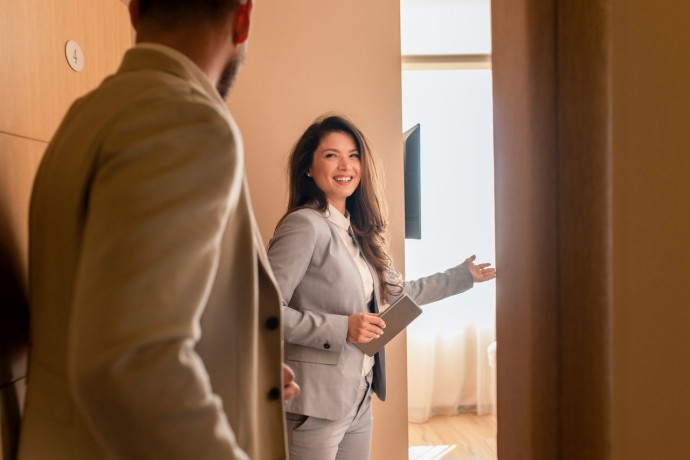 Young businessman check-in in hotel, smiling female receptionist showing him available rooms.