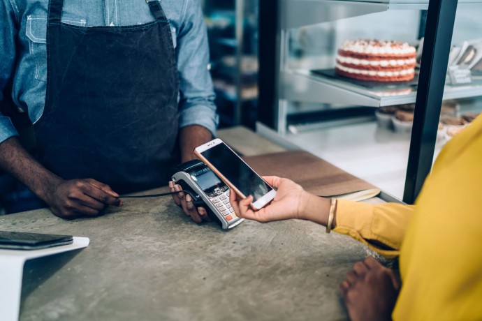 EY - Woman making payment with smartphone in cafe