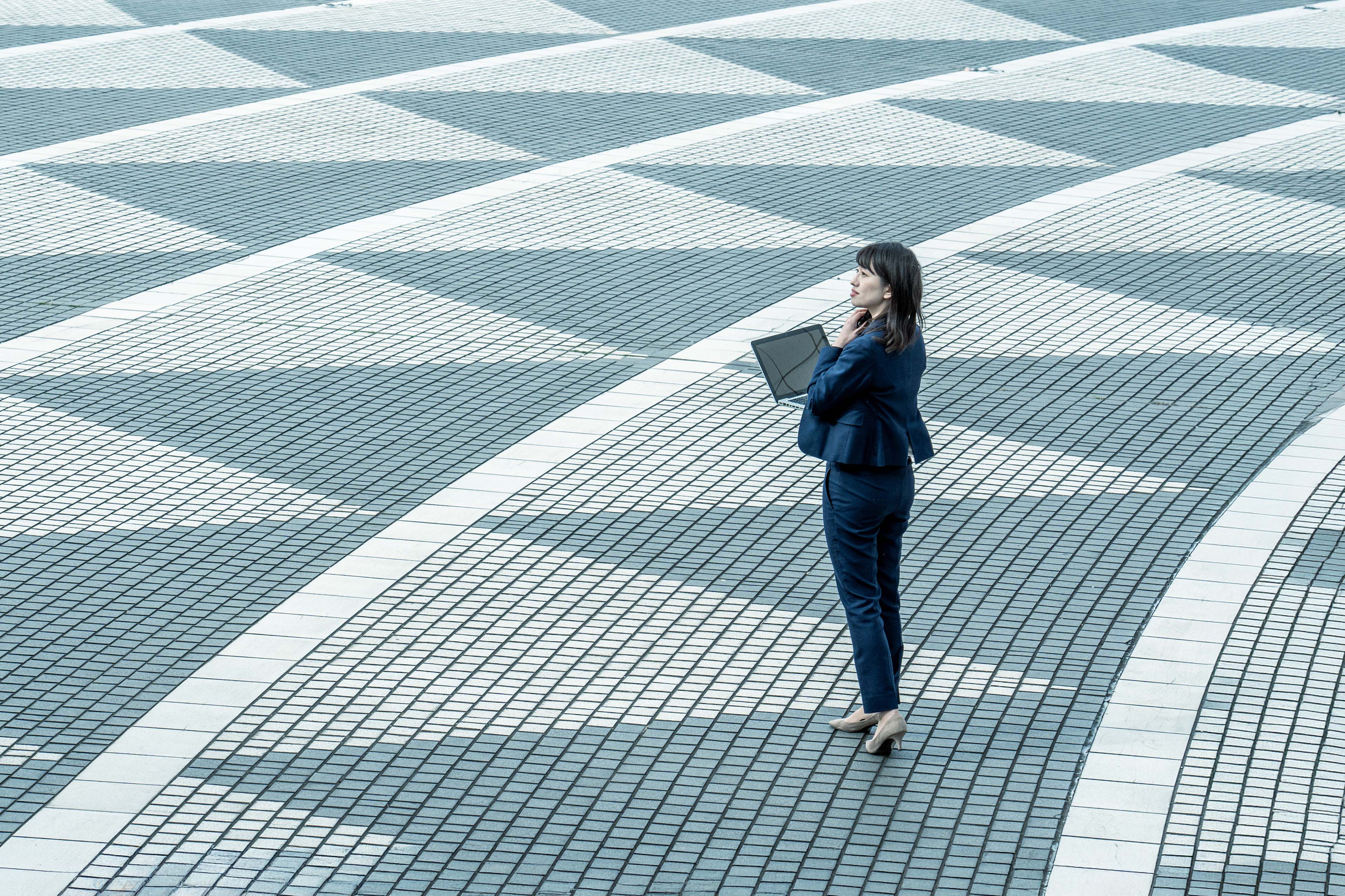 Photograph of a woman with a laptop on mosaic floor