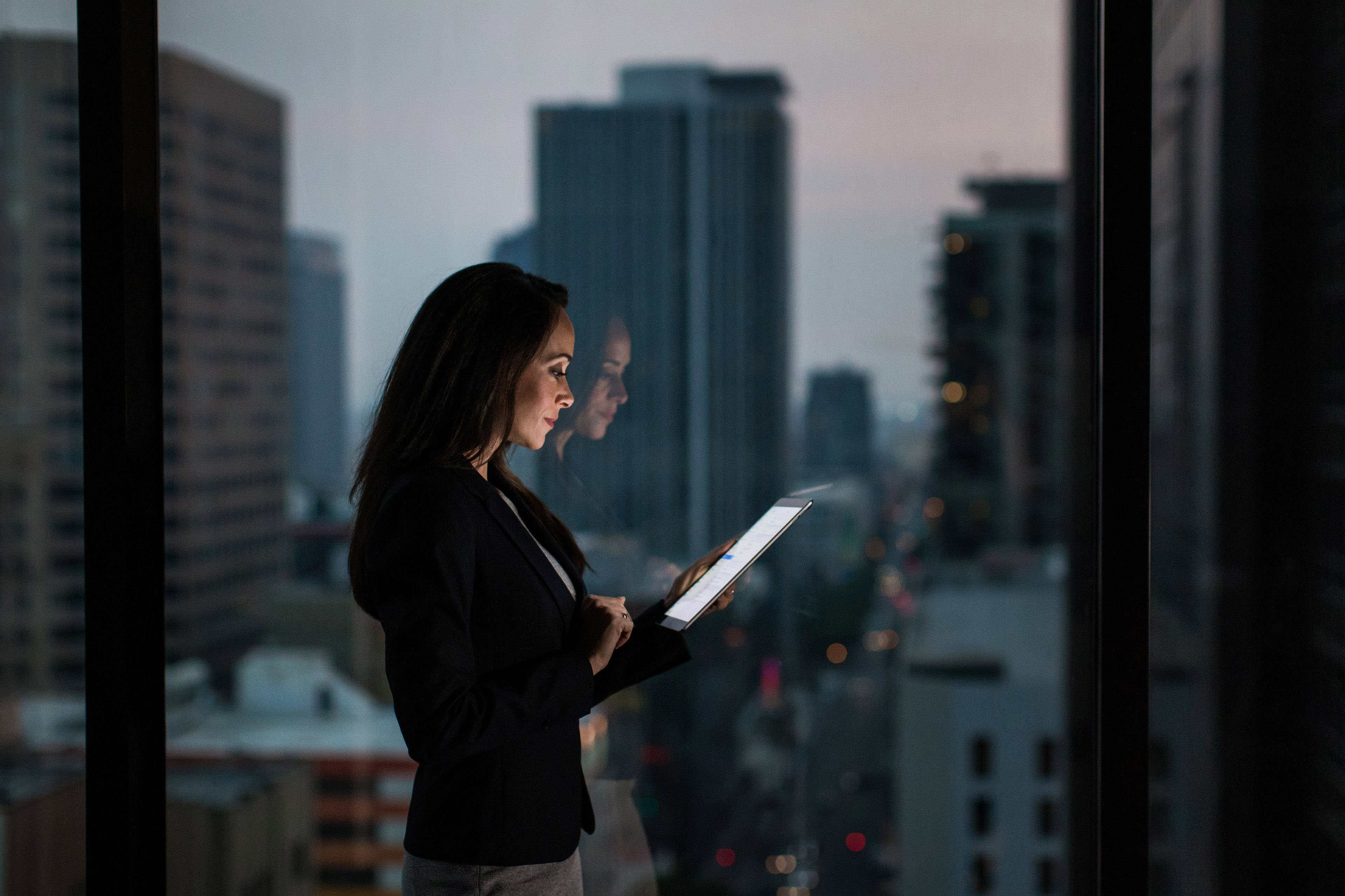 Businesswoman using digital tablet with city skyline in background