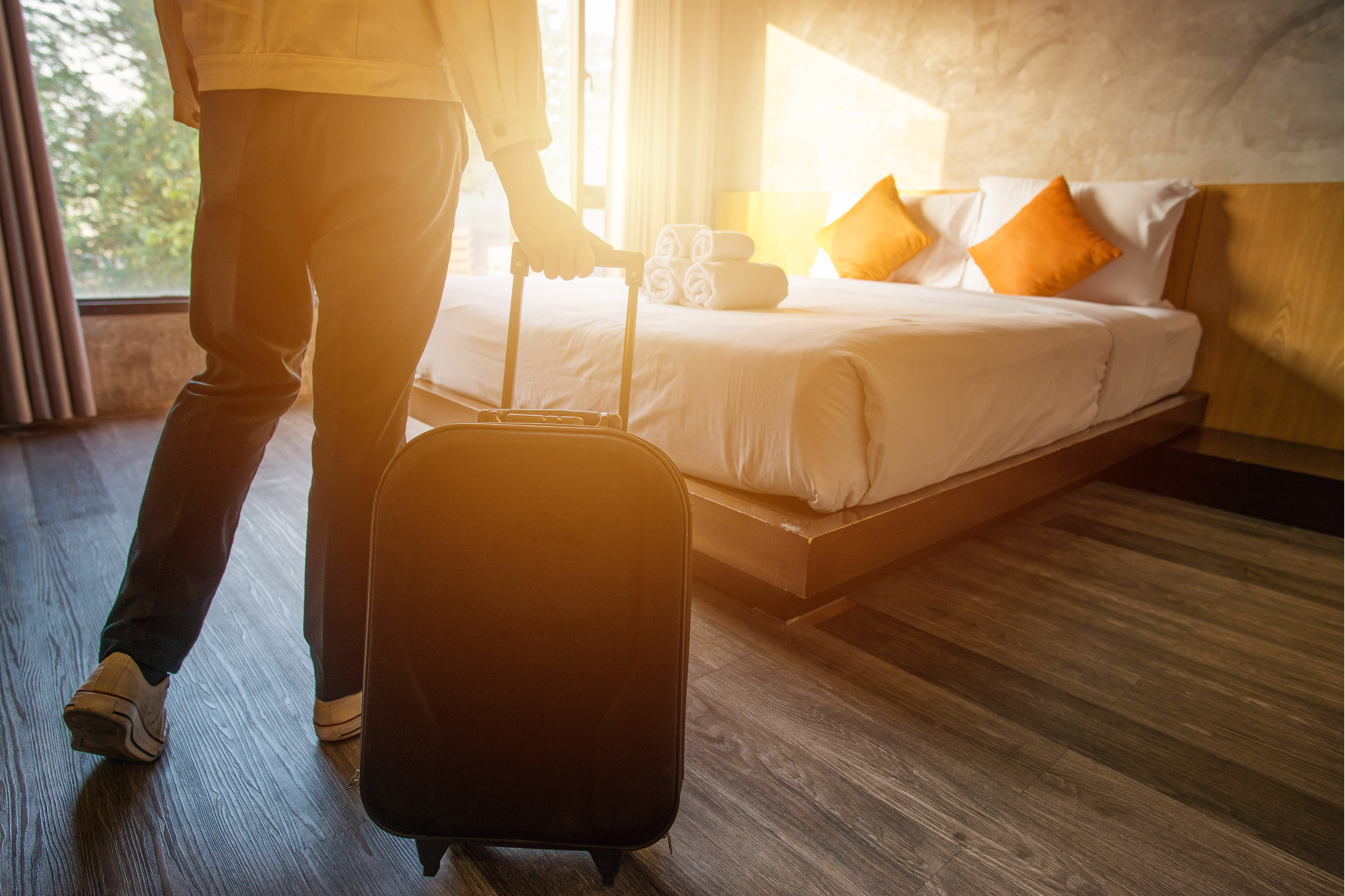 Traveler pulling a suitcase into a hotel room.