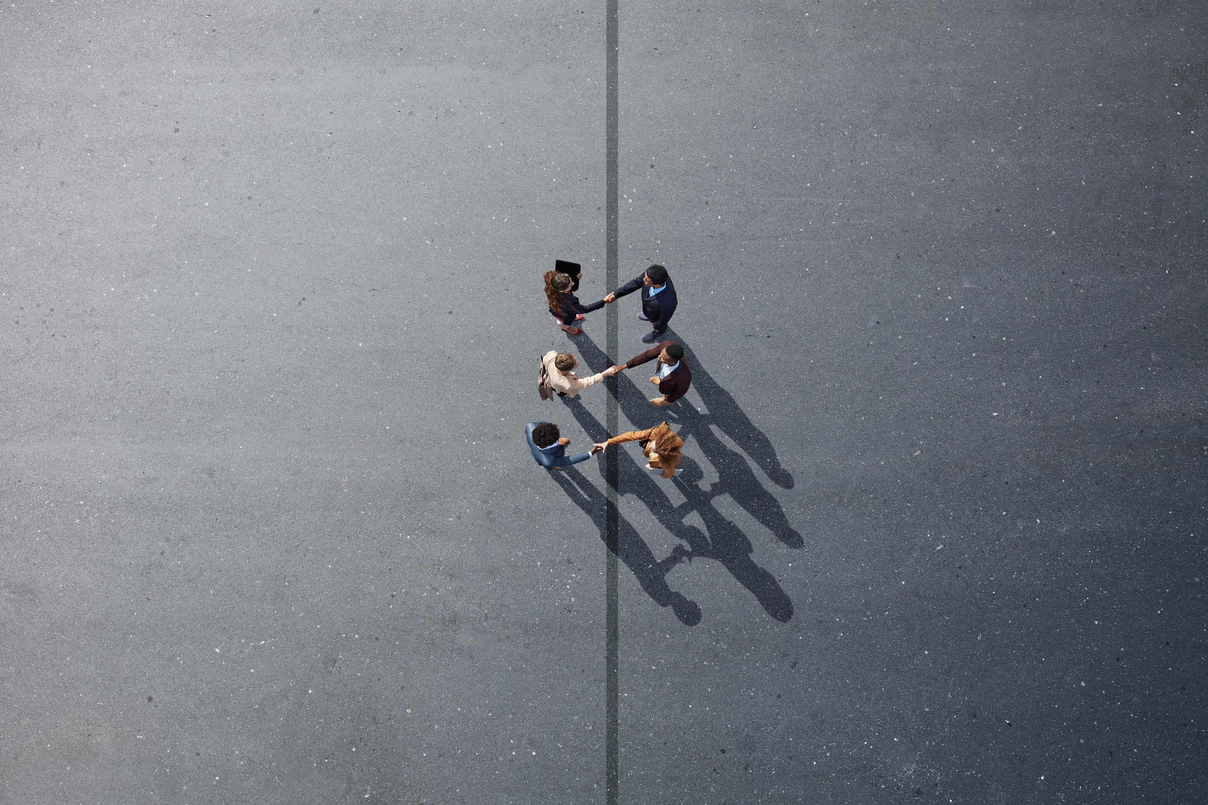 Groupe de personnes en cercle se serrant la main dehors