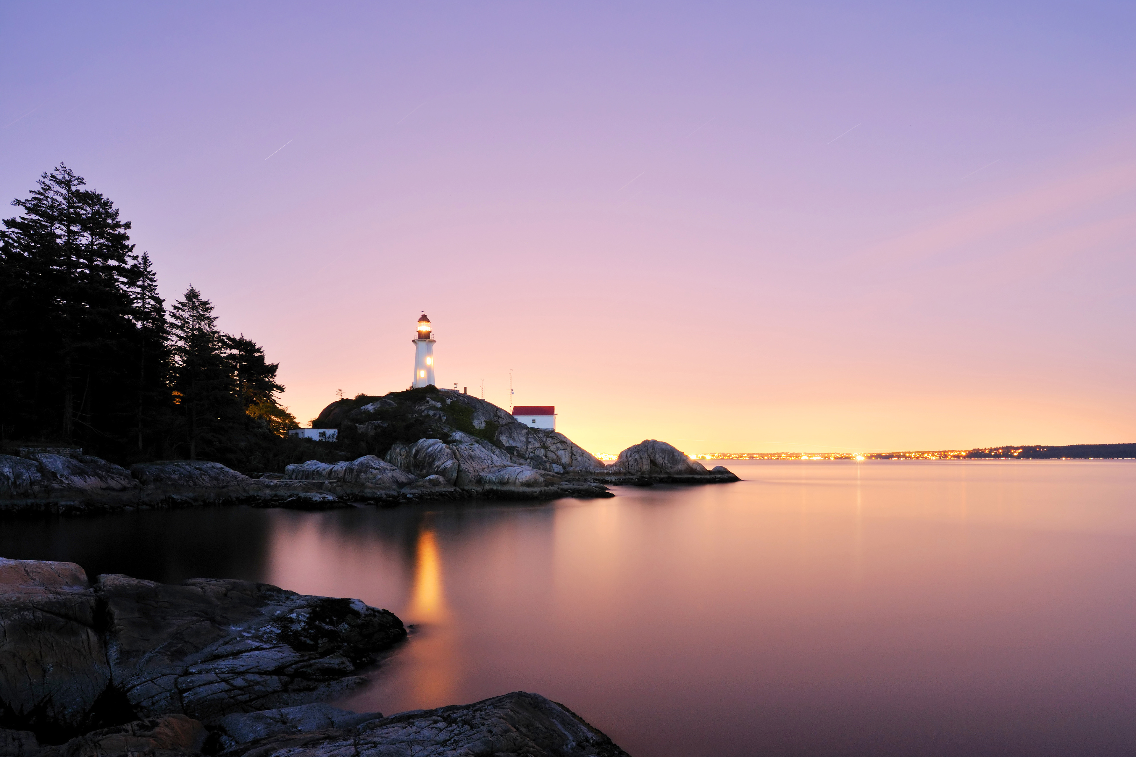 Phare sur cote rocheuse au crepuscule avec eau calme