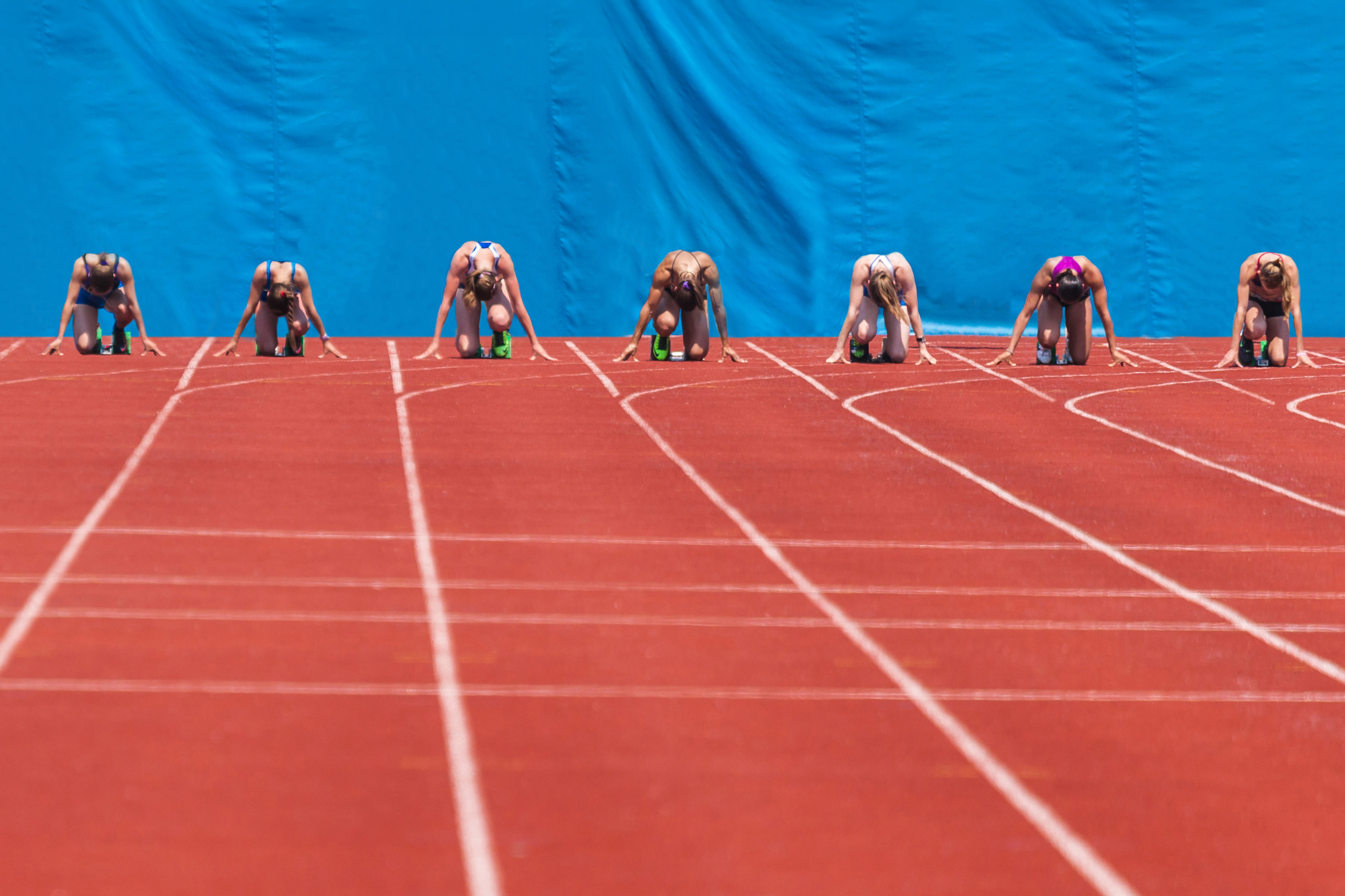 Sprinters zitten klaar aan de startlijn op een rode atletiekbaan
