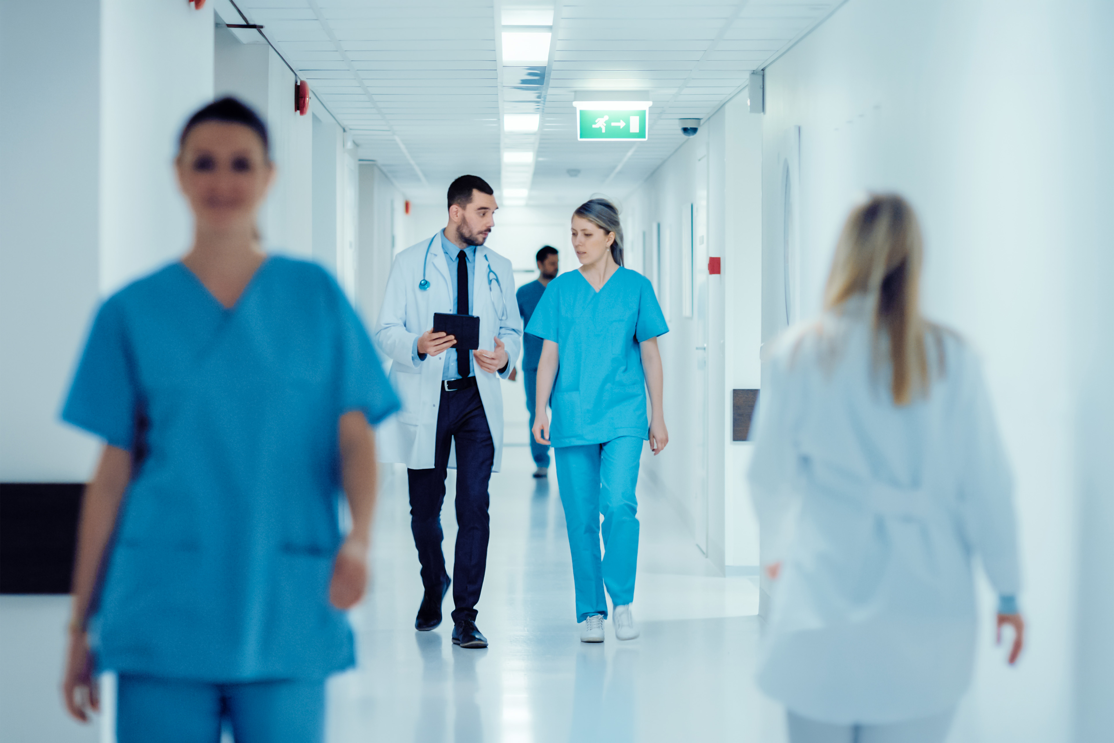 Surgeon and Female Doctor Walk Through Hospital Hallway