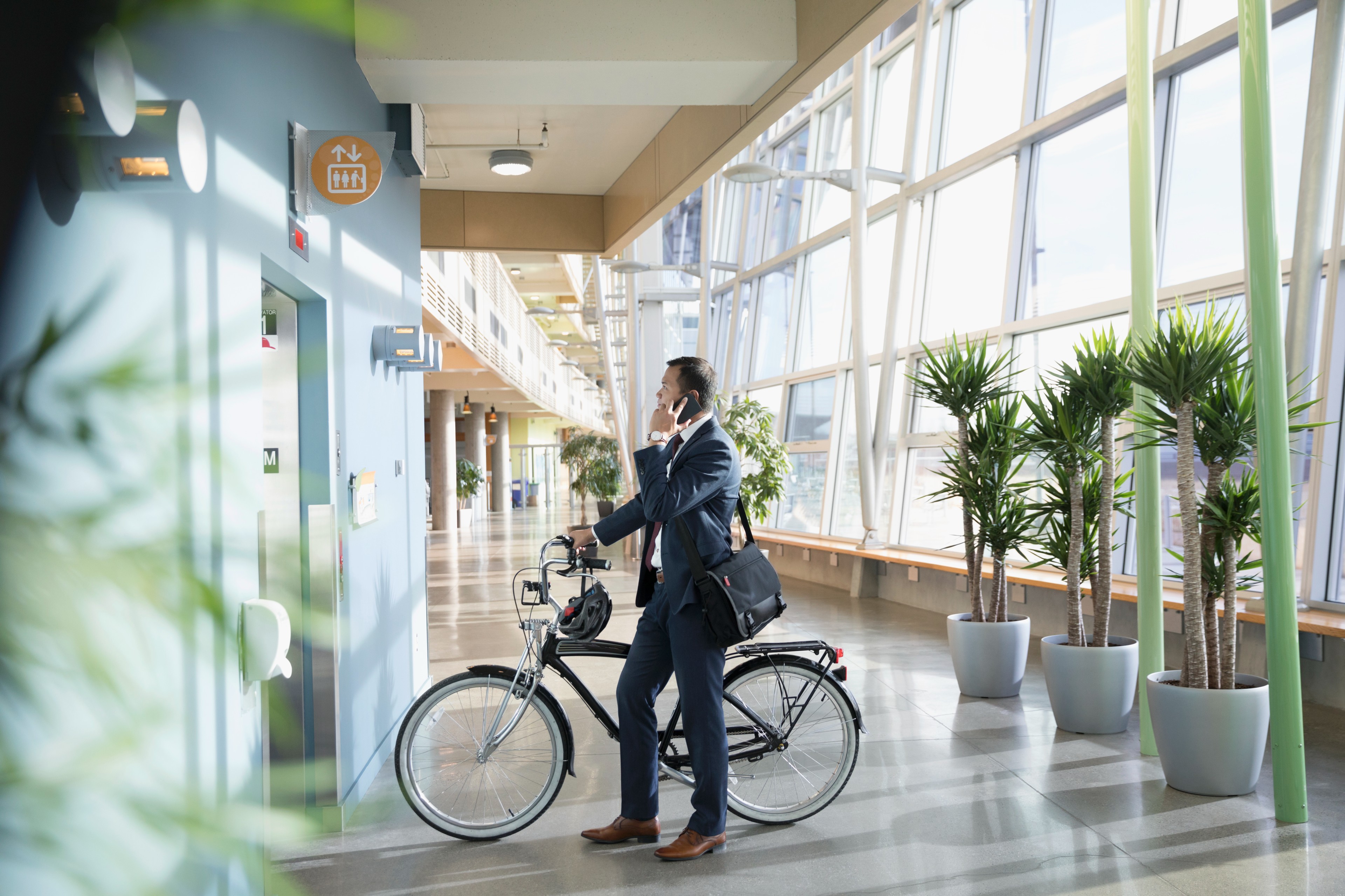 Businessman bicycle talking phone waiting elevator office lobby