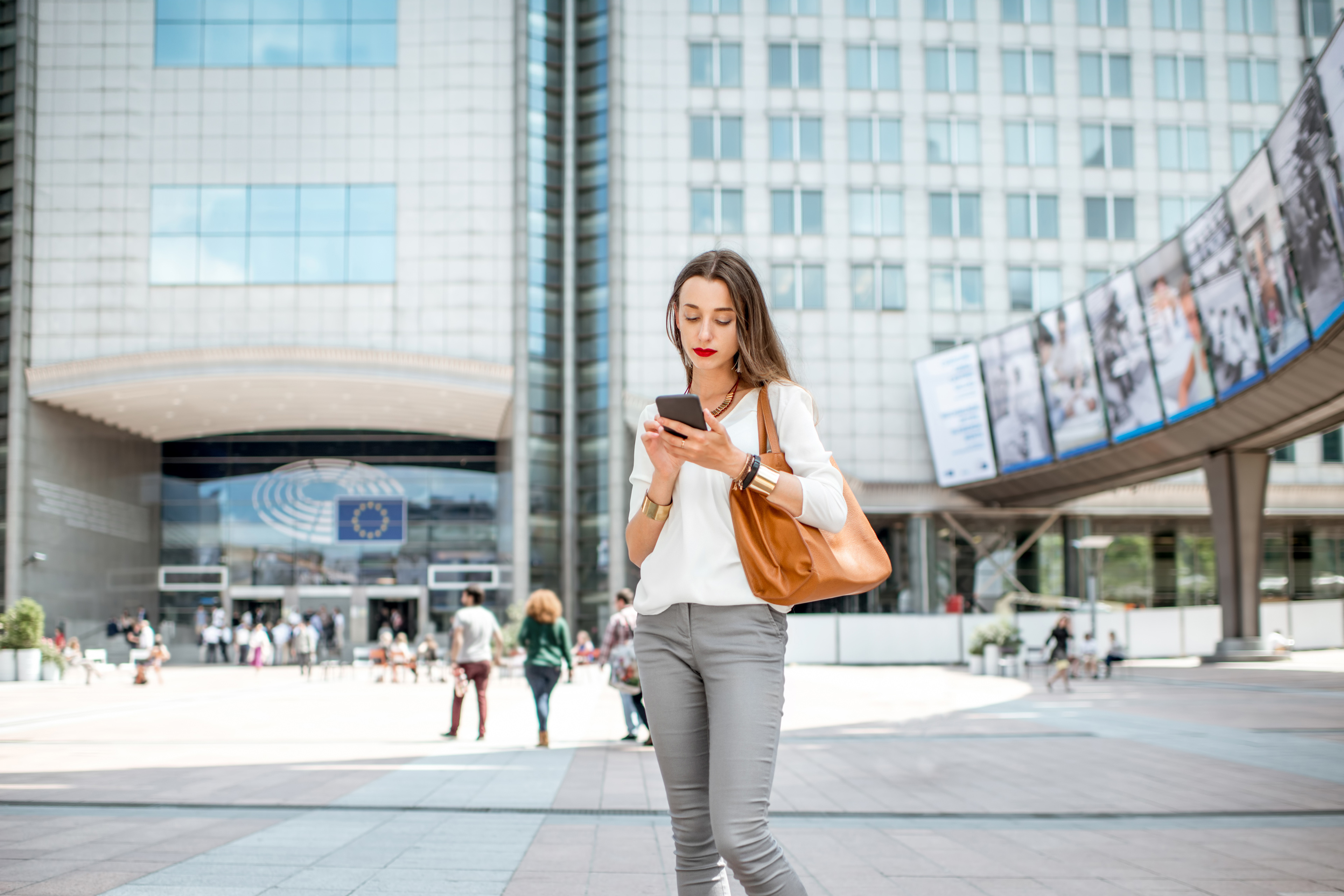 Young businesswoman standing with phone near the Parliament building