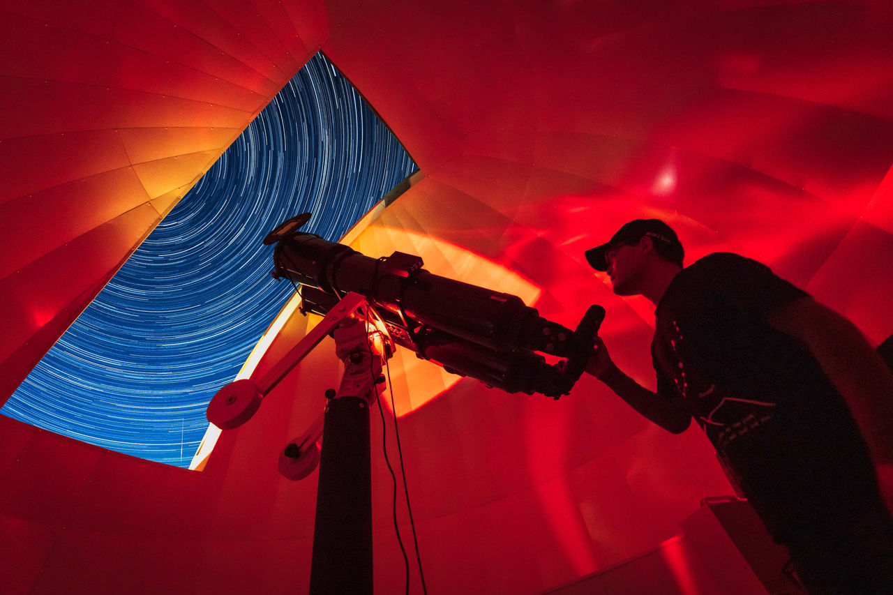 Astronomer in photo telescope dome with red light