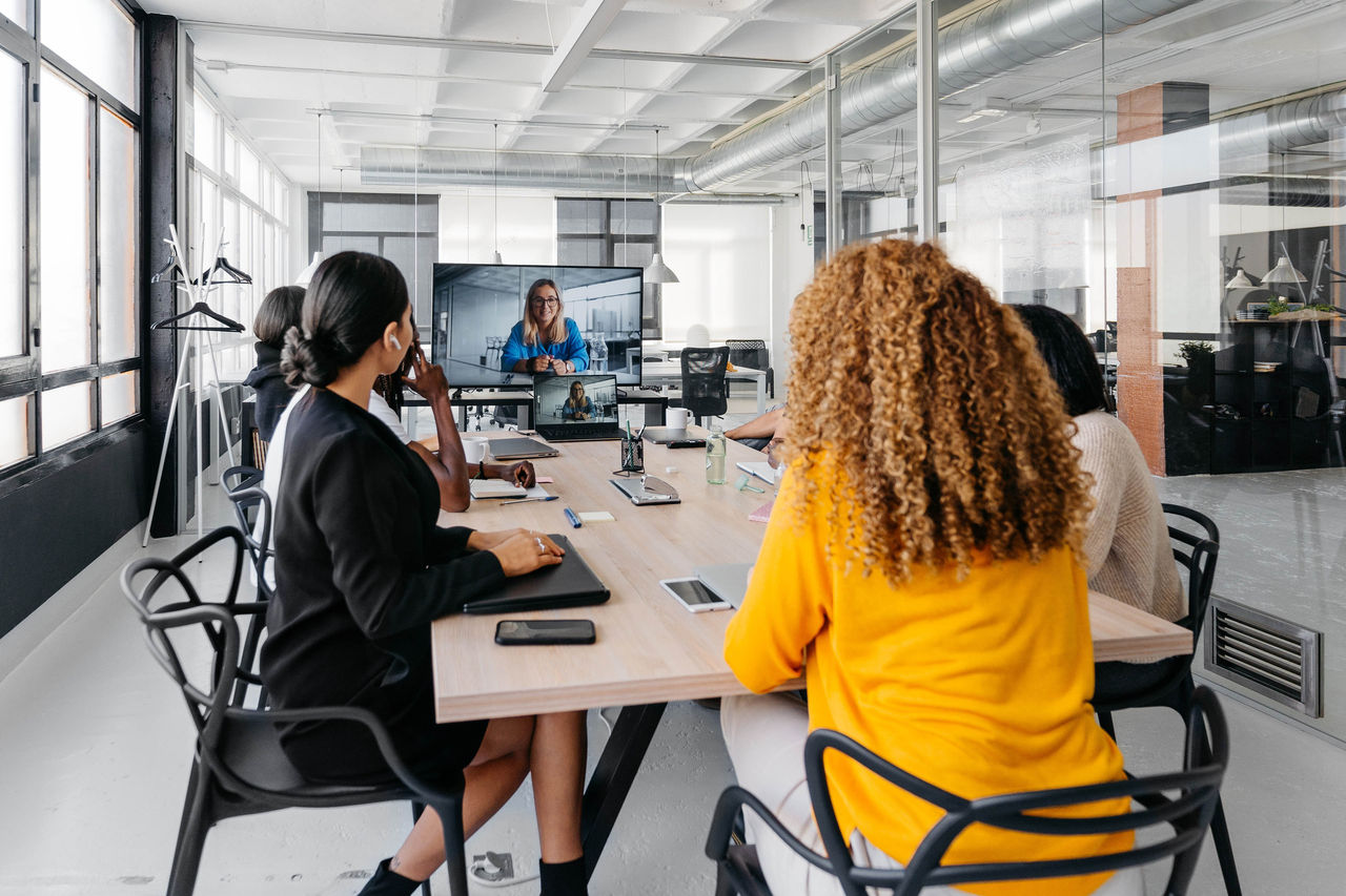 Group of multiracial businesspeople sitting around table having a remote video conference in modern workplace