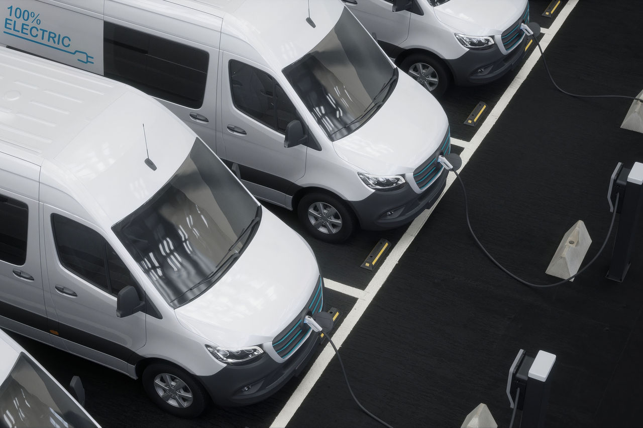 HIGH ANGLE Fleet of generic electric EV delivery vans charging on charging stations inside company parking garage
