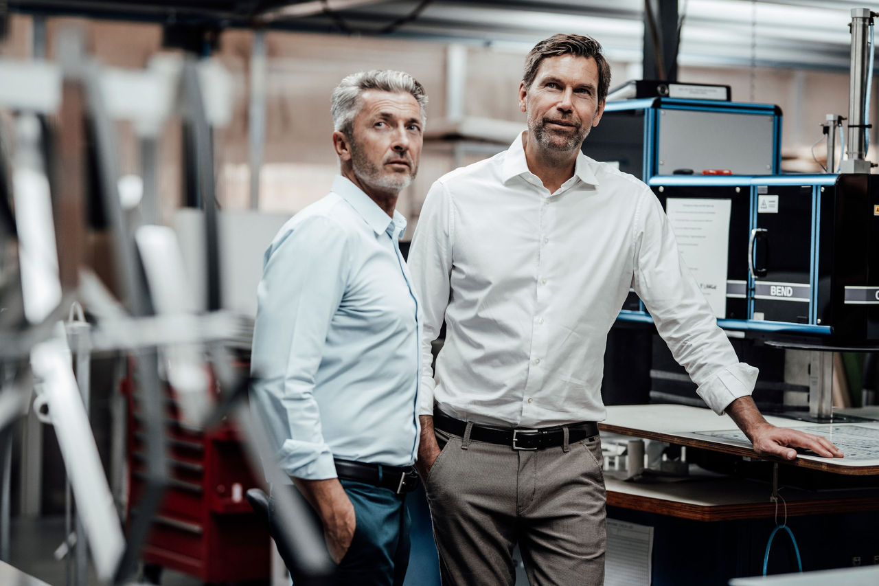 Zwei Männer stehen neben einer Maschine und betrachten den Bericht.