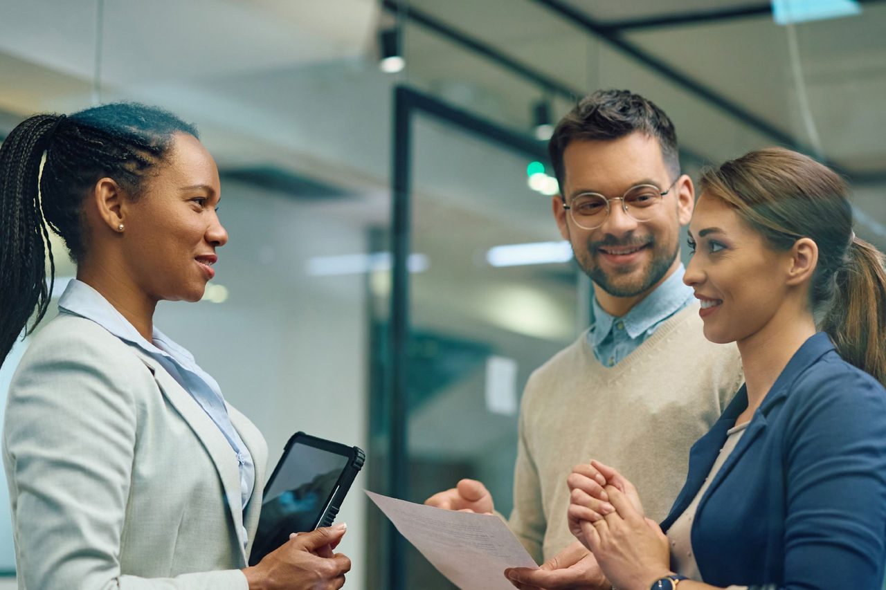Drei Fachleute in Business-Kleidung besprechen wichtige Informationen in einer modernen Büroumgebung.