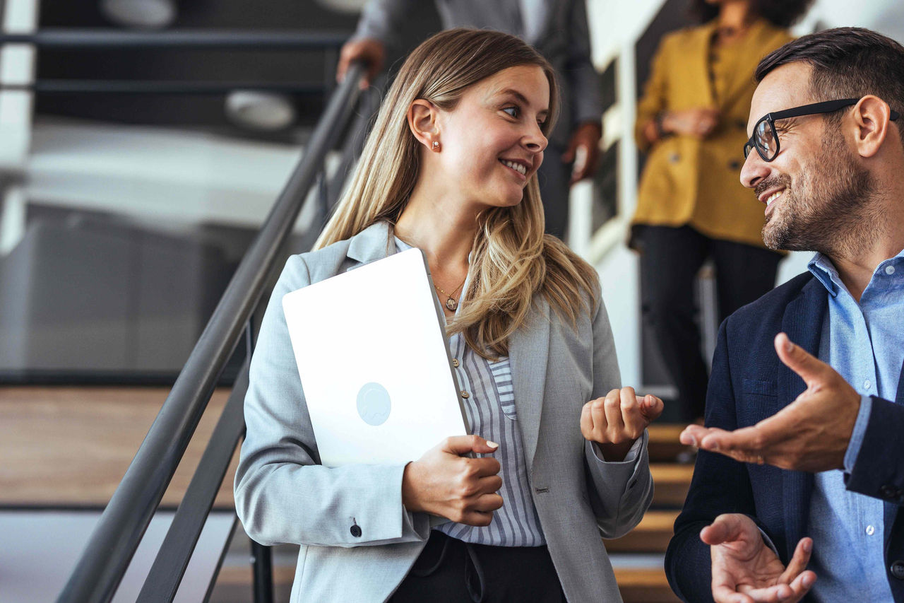 Kollegen sprechen miteinander, während sie eine moderne Bürotreppe hinabgehen.