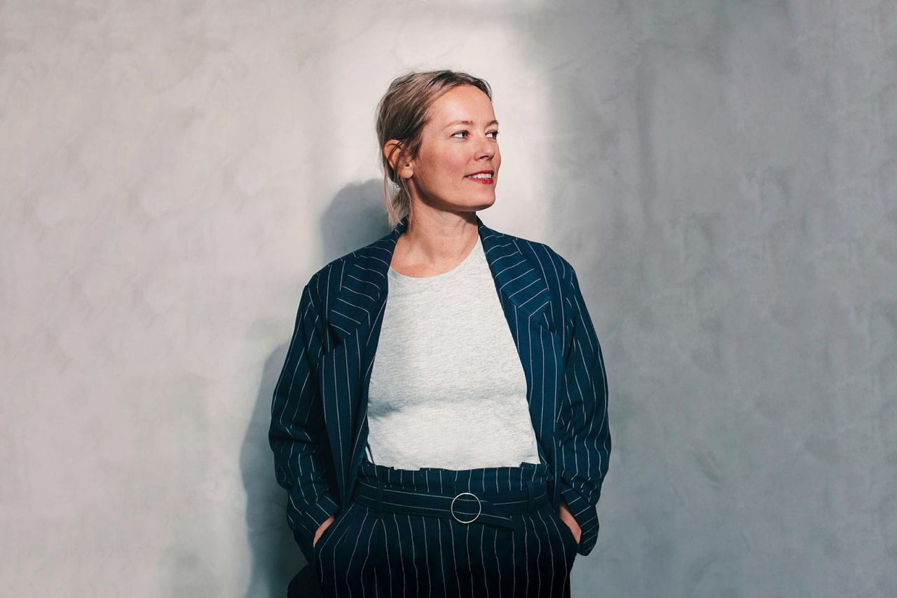 Eine Person steht entspannt vor einer modernen Wandstruktur.