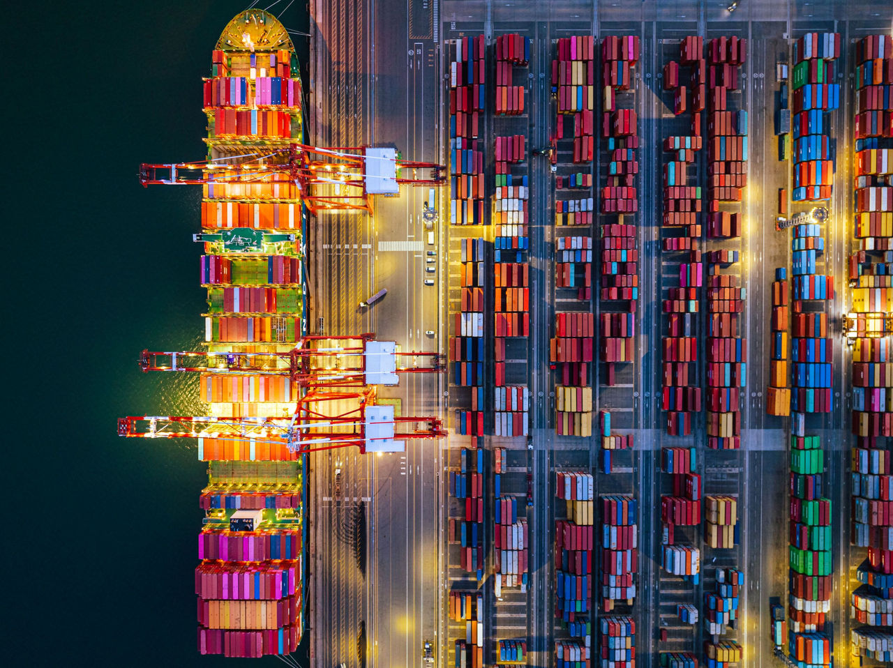 Luftaufnahme eines Frachtschiffs im Containerhafen mit bunten Schiffscontainern für den globalen Handel.