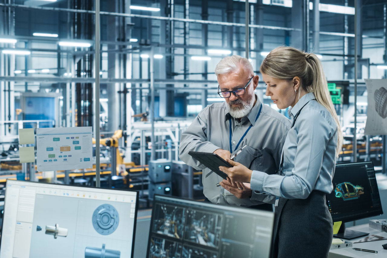 Ingenieure überprüfen Produktionsdaten auf einem Tablet in einer intelligenten Fertigungsanlage.