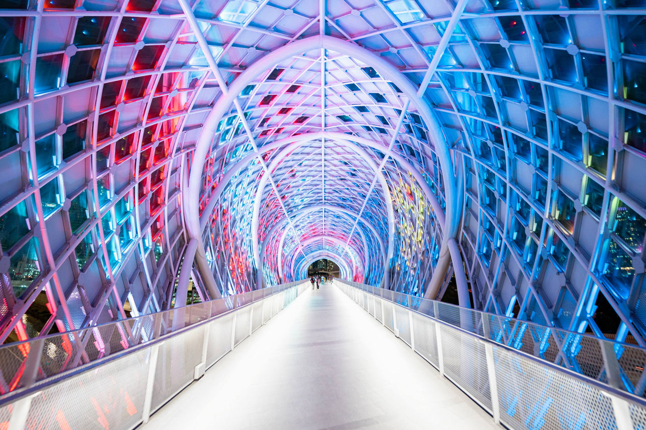Farbig beleuchteter Tunnel mit moderner, symmetrischer Architektur.