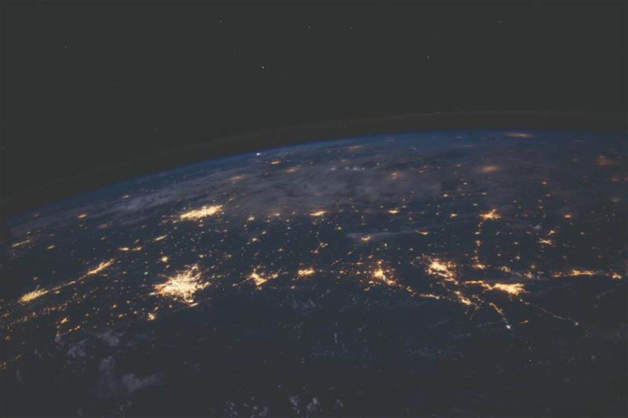 Blick aus dem Weltraum auf die Erde bei Nacht mit leuchtenden Städten und Kontinenten.