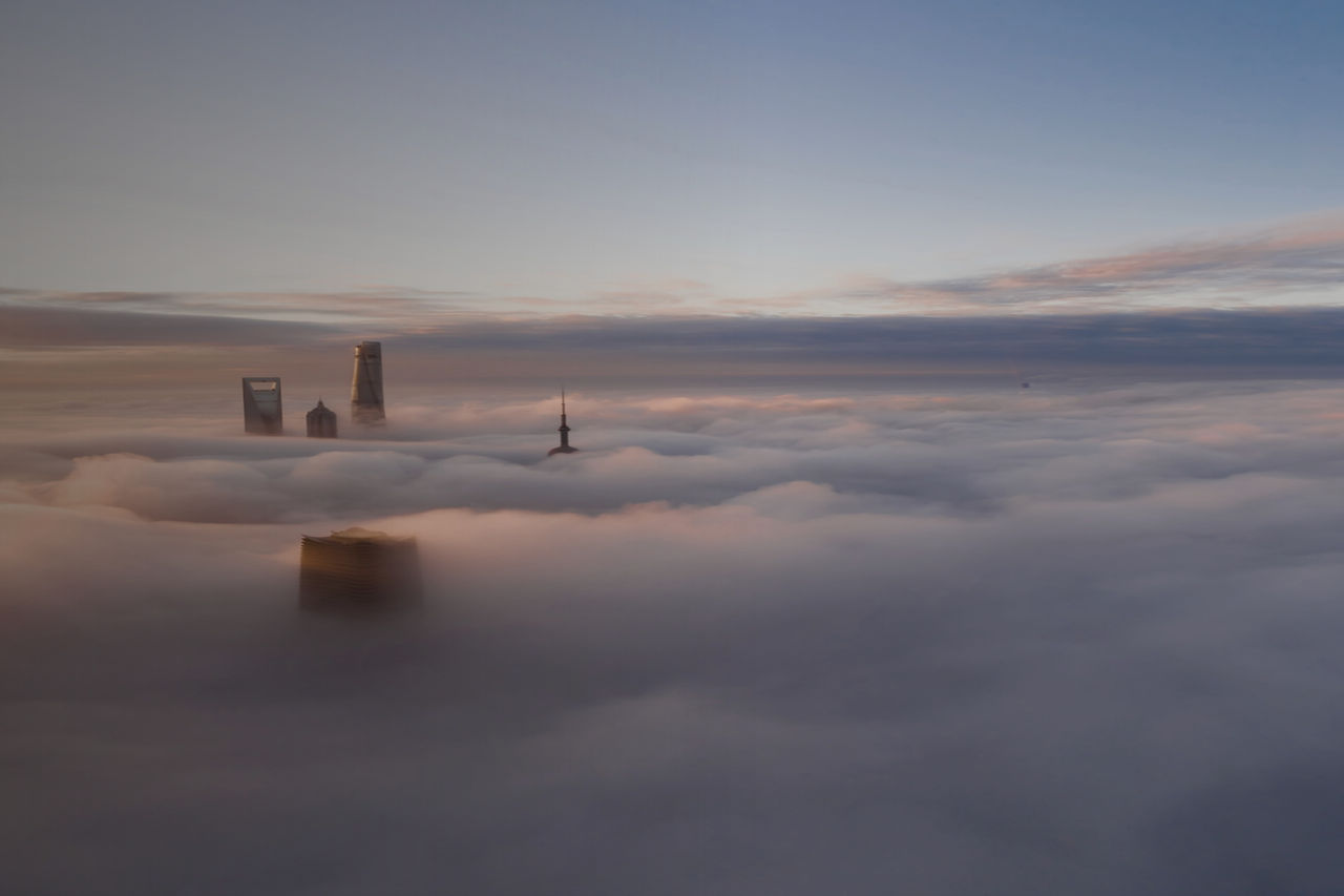 Stadtsilhouette in Deutschland ragt bei Sonnenaufgang über einem dichten Nebelmeer mit modernen Hochhäusern