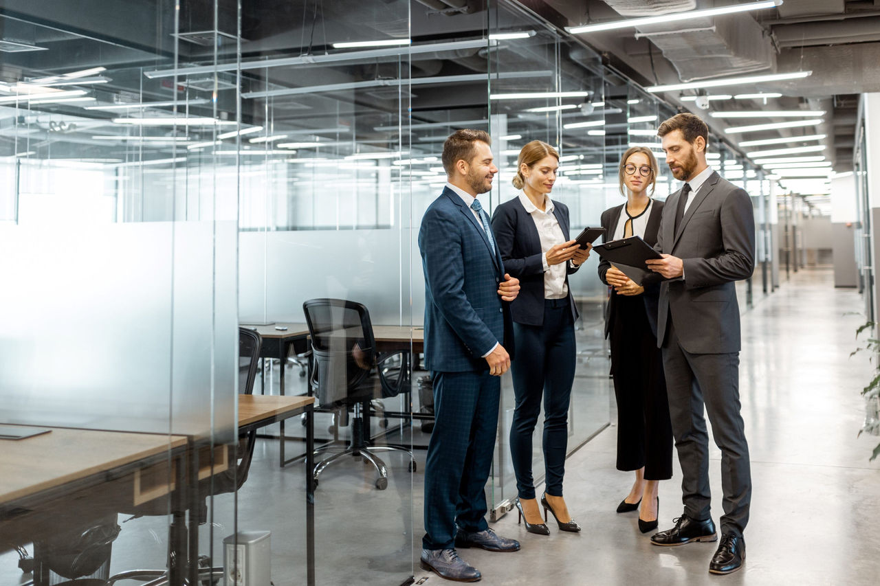 Fachkräfte besprechen Unterlagen und digitale Inhalte in einem modernen Bürogebäude.