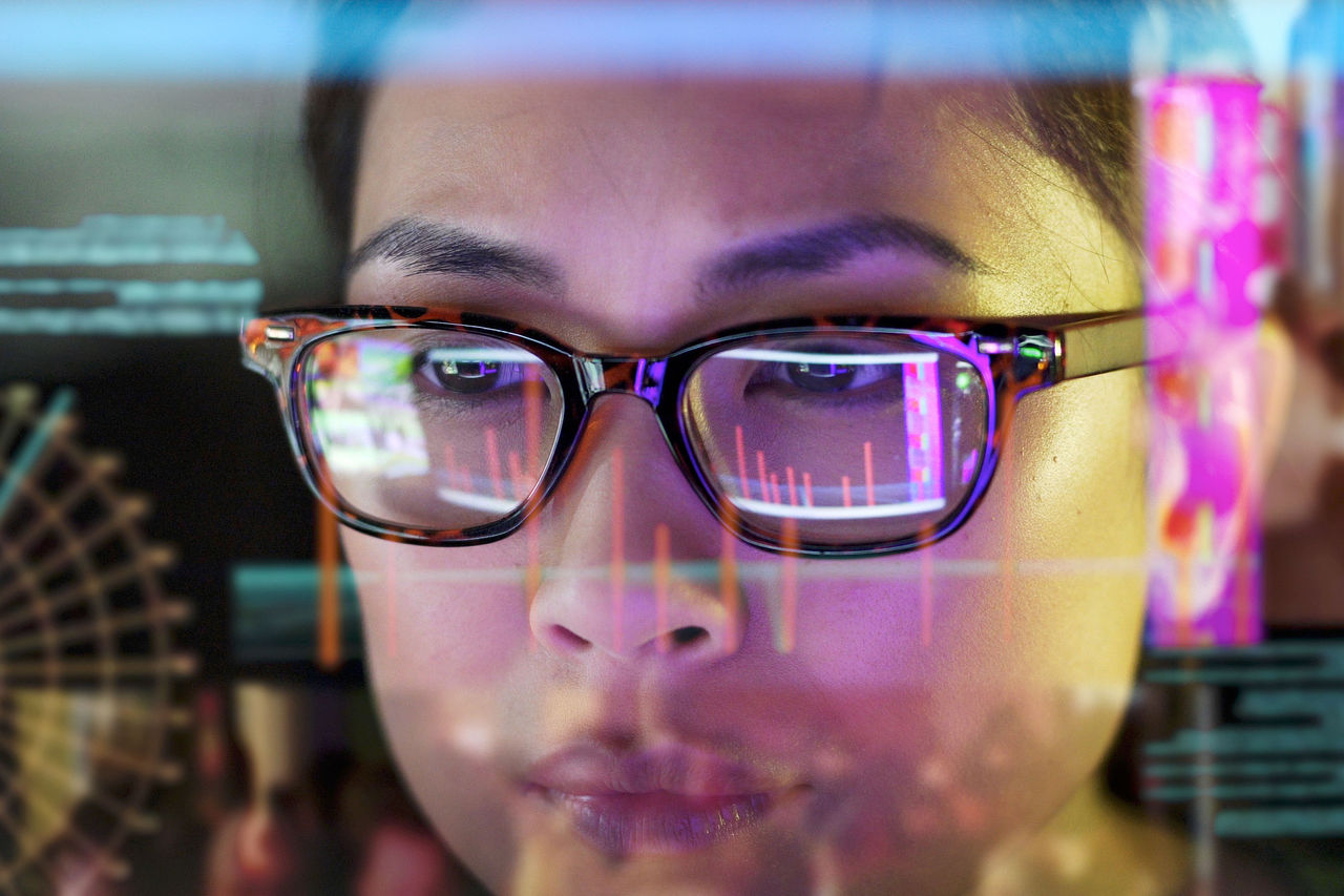 Nahaufnahme einer asiatischen Frau, die sorgfältig bewegliche Daten auf ihrem Computerbildschirm studiert.