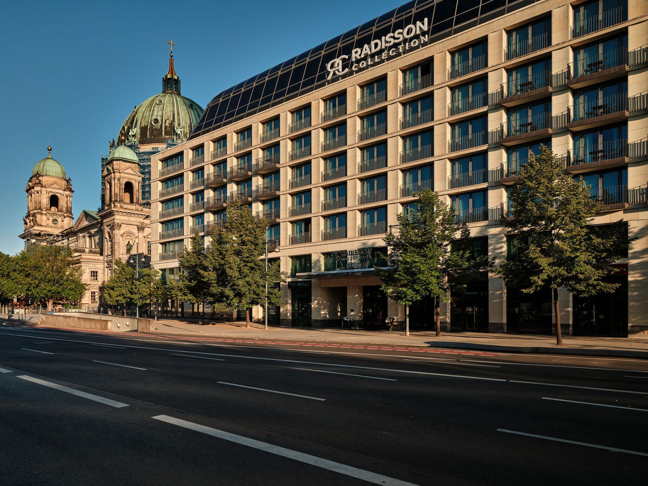Das Radisson Hotel in Berlin im Vordergrund mit dem Berliner Dom im Hintergrund bei Sonnenschein
