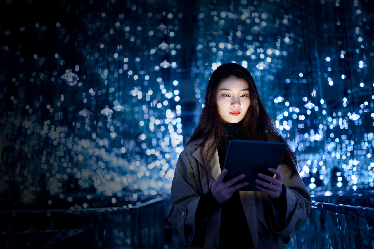 woman using digital tablet against illuminated background